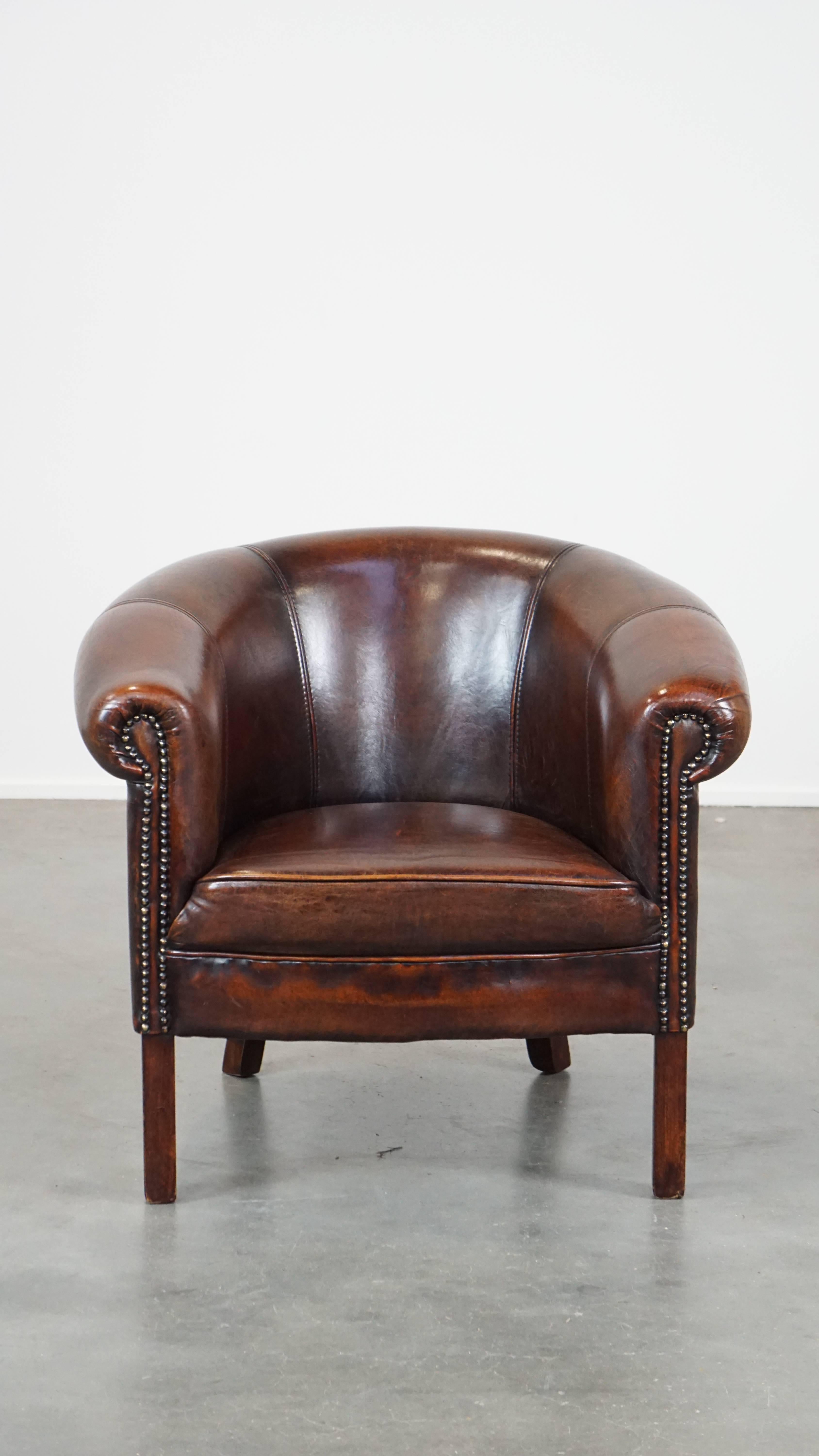 This beautiful sheepskin leather club armchair, despite its subtle size, perfectly exudes English elegance and class. It is a stunning addition for enthusiasts. The club chair is in good condition and is finely finished with decorative nails. It