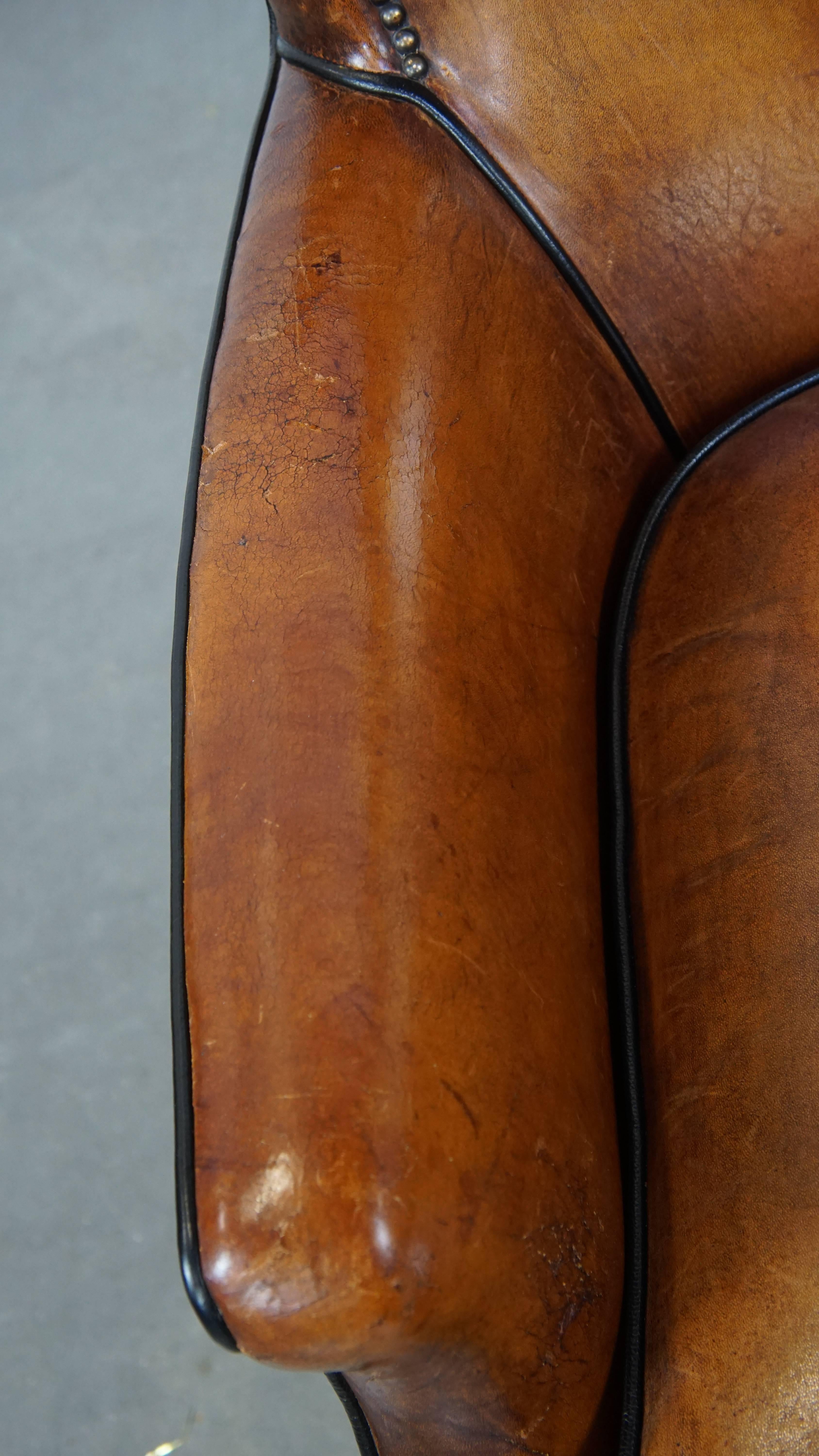 Poltrona in pelle di pecora color cognac con profili neri e chiodi decorativi in vendita 1