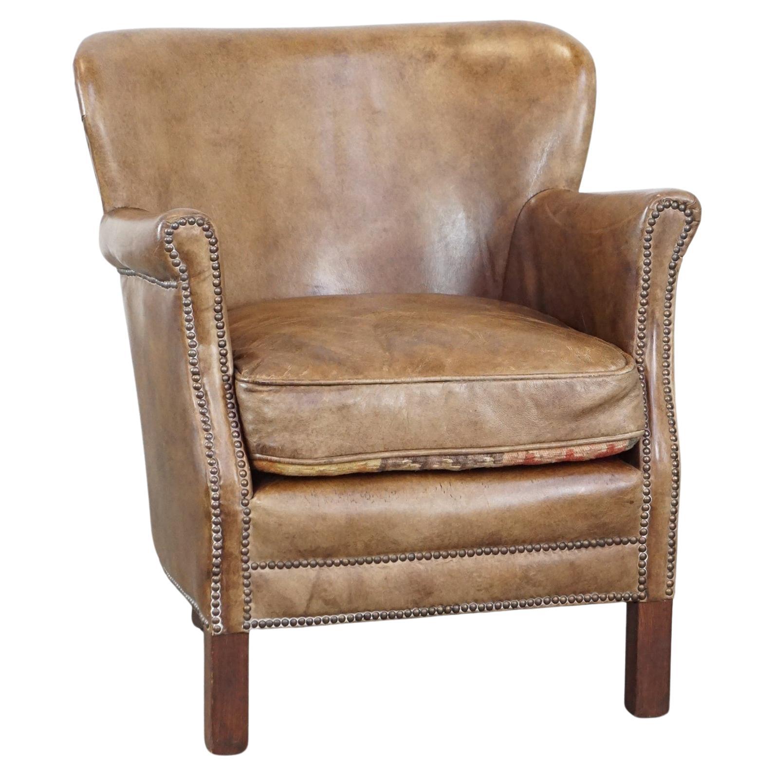 Subtle leather armchair with a reversible kilim seat cushion