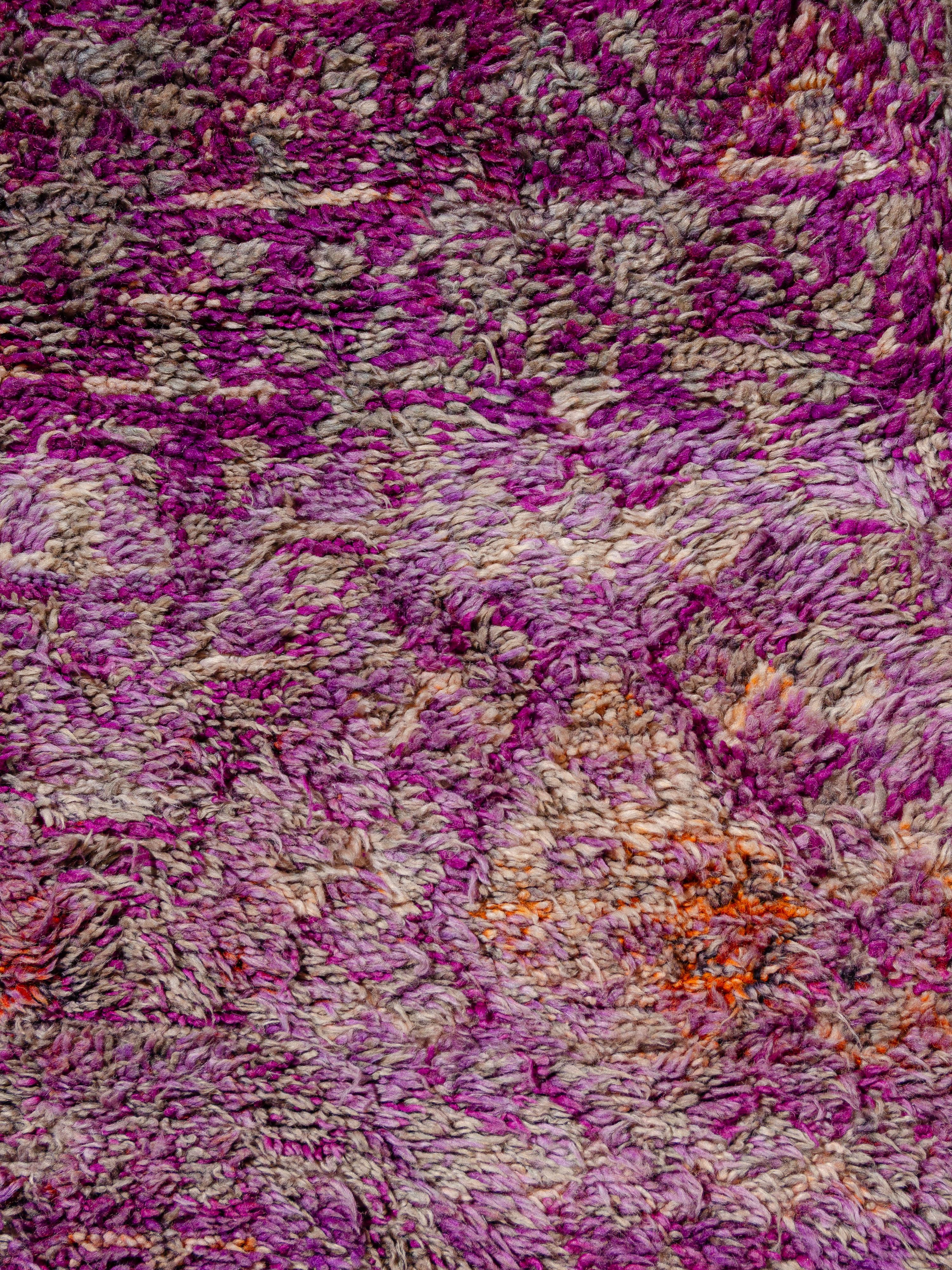 Dieser alte marokkanische Beni M'Guild-Teppich zeigt ein diffuses Rautennetz mit offenen V-Formen, Dreiecken und Pfeilen. Gewebt in einer einzigartigen Farbpalette aus abgewetztem Violett und Magenta, mit Akzenten in Korallenrot, leuchtendem Orange