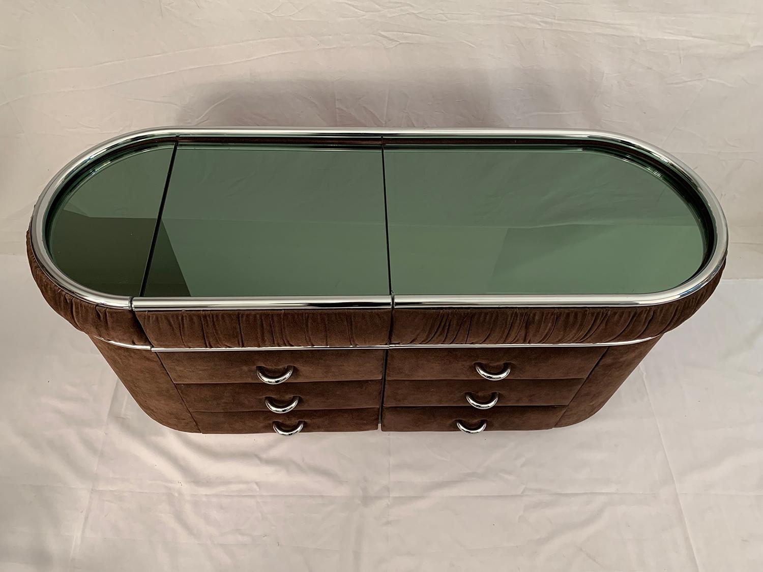 Very nice vanity cabinet covered with brown suede. Handles and contour are made of chrome. A mirror with light green reflects embellishes the top of the cabinet, 1970s.

Très joli meuble coiffeuse en daim marron avec poignée et contour en chrome