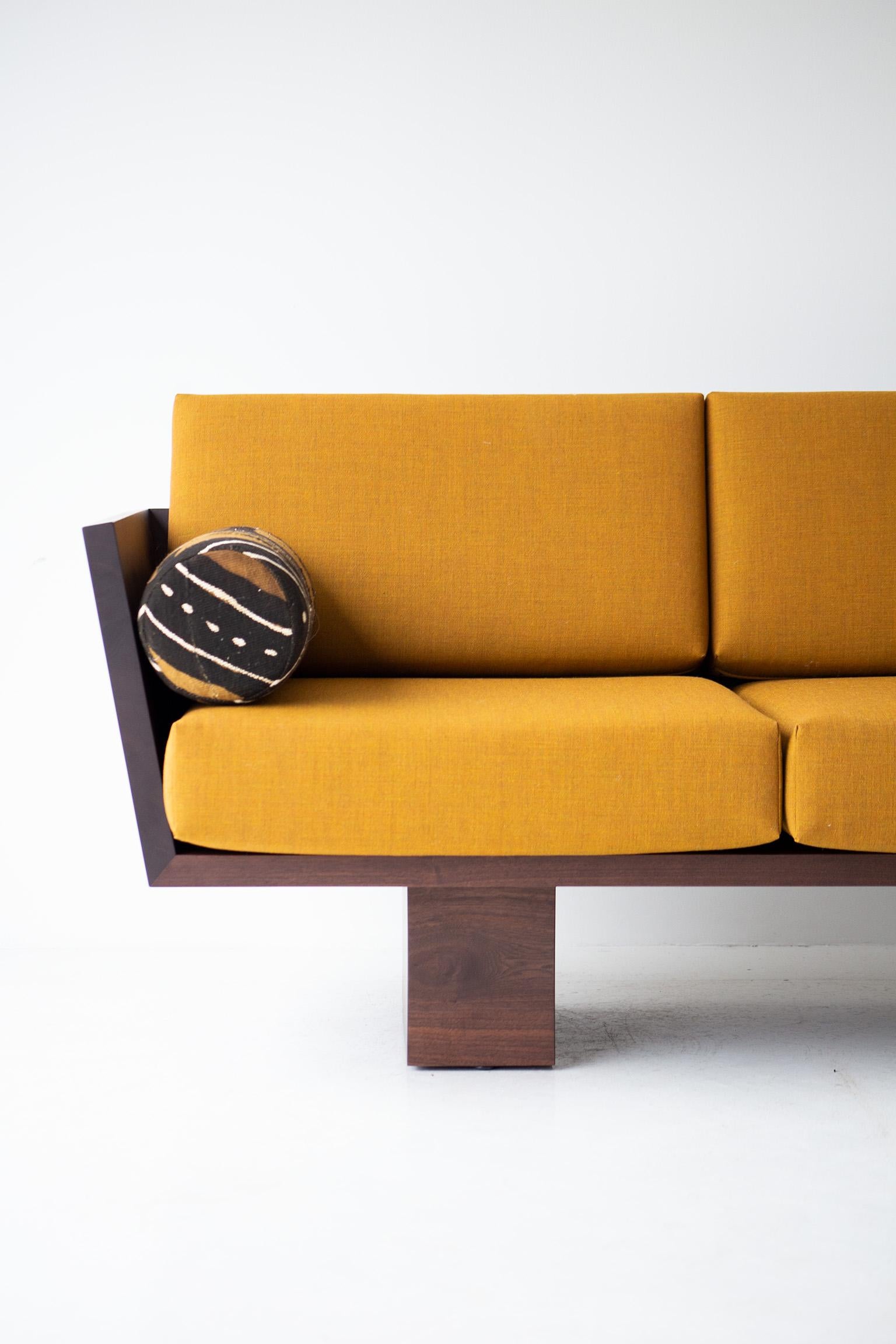 Ce canapé Suelo Modern Wood en noyer massif est magnifiquement construit en bois massif dans l'Ohio, aux États-Unis. La silhouette du canapé est simple, moderne et élégante, avec des coussins de siège et de dossier confortables. C'est le canapé