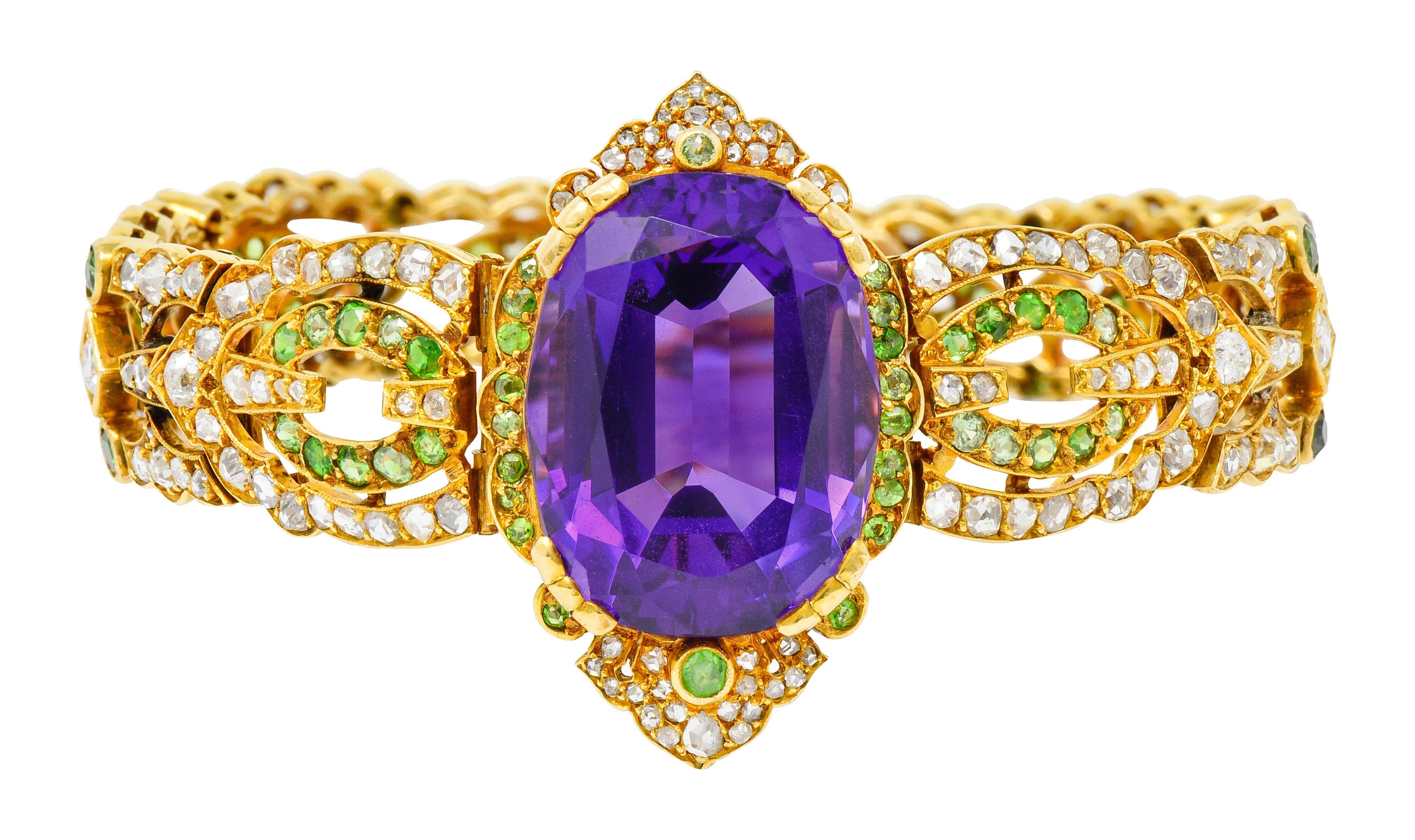 Link style bracelet with scalloped edges and a pierced navette design accented throughout by demantoid garnets and diamonds

Centering an oval cut amethyst measuring approximately 21.5 x 16.8 mm; transparent and robustly purple

Round cut demantoid
