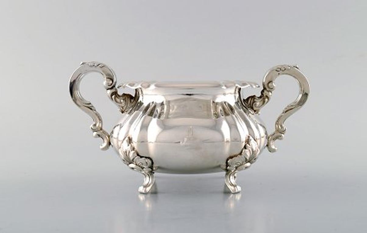 Sugar bowl and creamer in silver on feet. Rococo style, 1920s-1930s.
In very good condition.
Stamped: 830SE.
The sugar bowl measures: 18 x 9 cm.
The creamer measures: 12.5 x 10 cm.
Total weight: 424 grams.