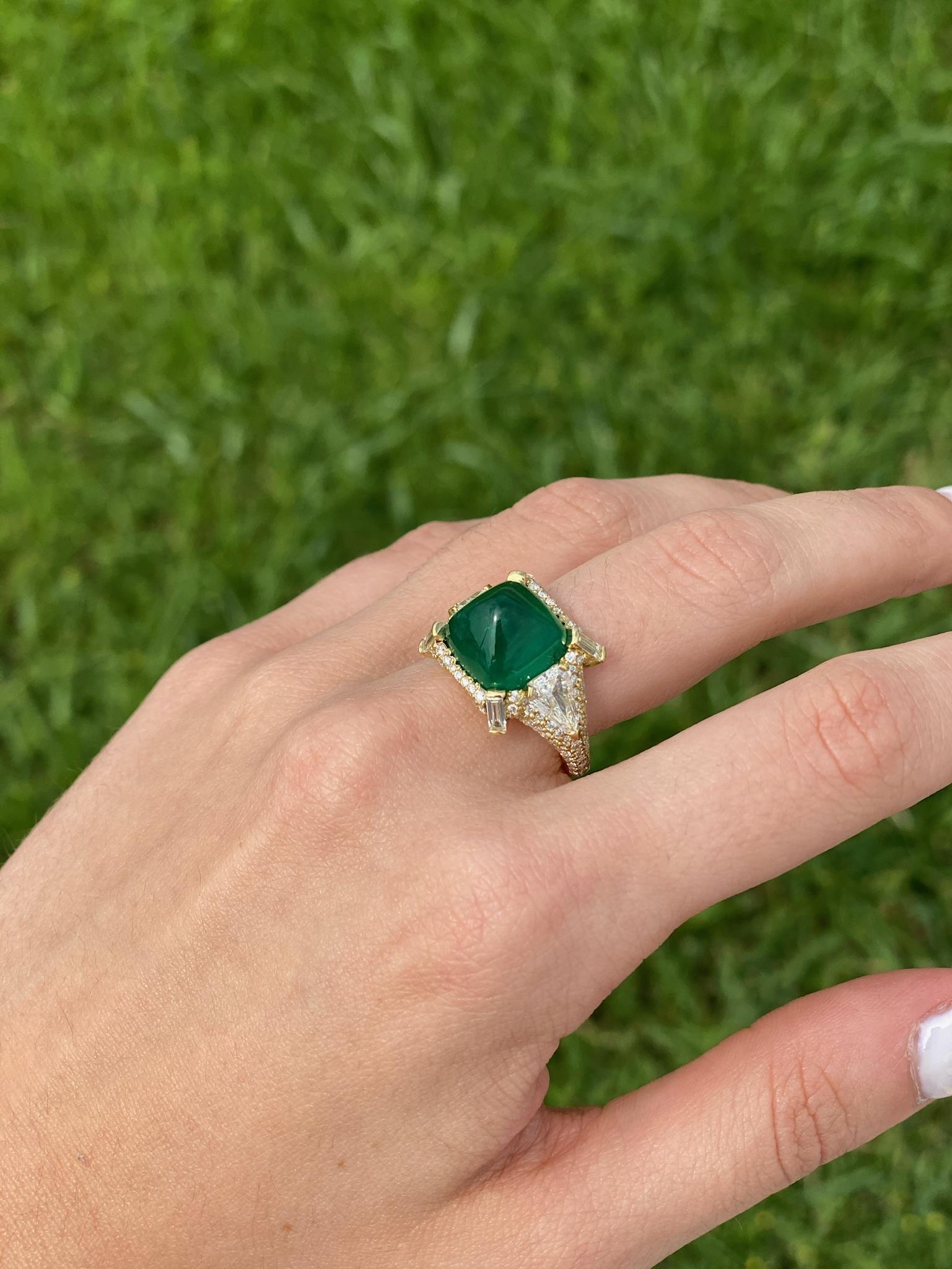 A very important 9.08 carat sugarloaf cabochon Emerald ring complimented with Diamonds by Andrew Glassford. This one-of-a-kind ring has a very intense large Emerald that is flanked by two shield shaped, step cut  GH VSI Diamonds that total 1.08