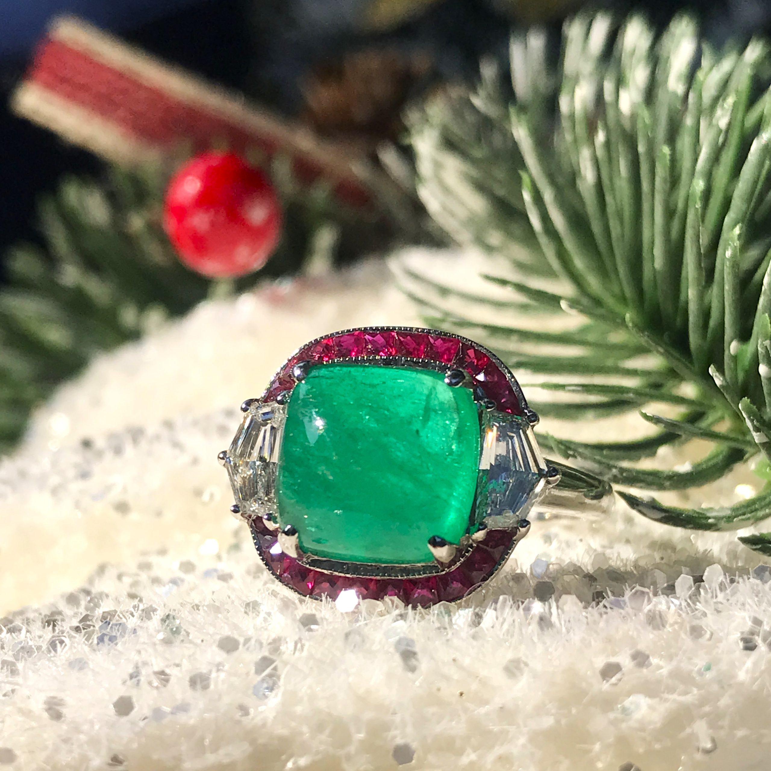Une magnifique émeraude colombienne certifiée de 4,12 carats en cabochon naturel est sertie dans un halo de 20 rubis de taille française. Une paire de diamants pesant 0,65 carat est flanquée de part et d'autre du halo et attachée à un anneau en or