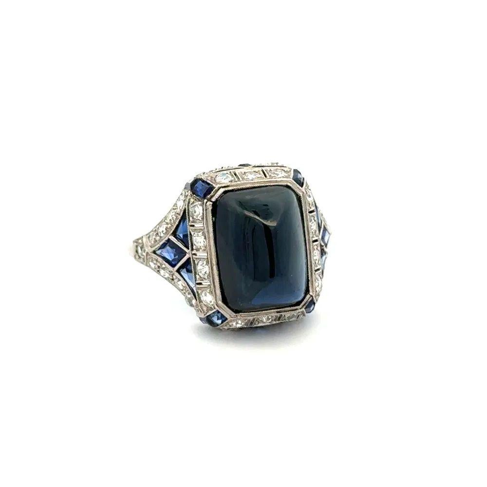 Sencillamente hermoso Anillo de cóctel vintage de zafiro azul y diamantes en platino. Centrado en un zafiro Sugarloaf de 12 quilates, rodeado de diamantes de 0,72 quilates y zafiros de 0,70 quilates. El anillo está hecho a mano en platino. Mide