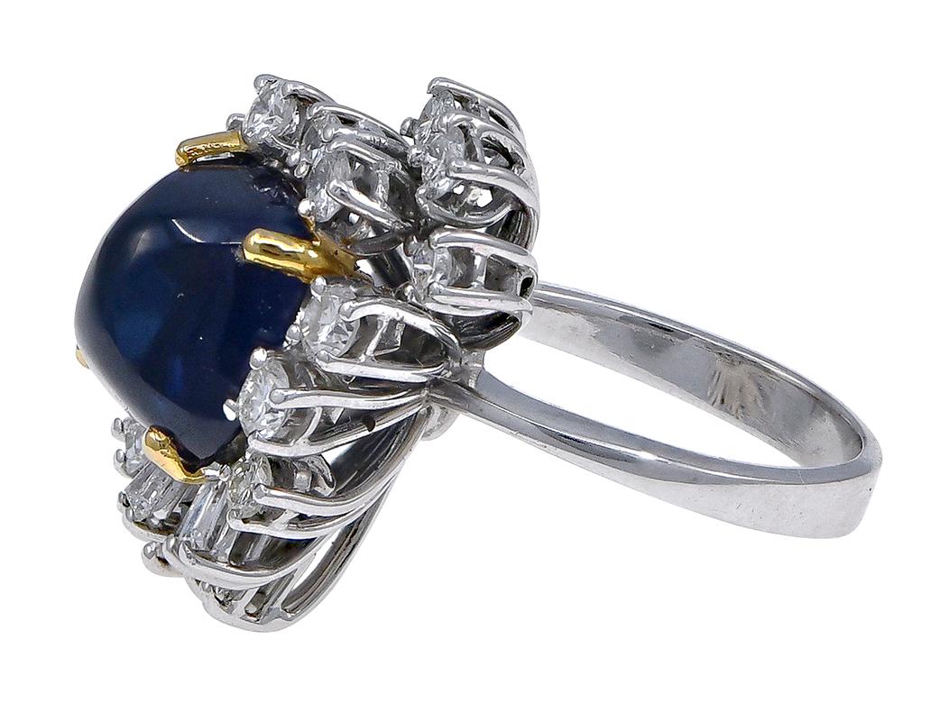 This is one impressive piece of jewelry! Crafted in 18K White Gold, the ring features a starburst design of yellow gold prong set Round and Baguette cut diamonds, with an exceptional natural cabochon sapphire center. The sapphire weighs