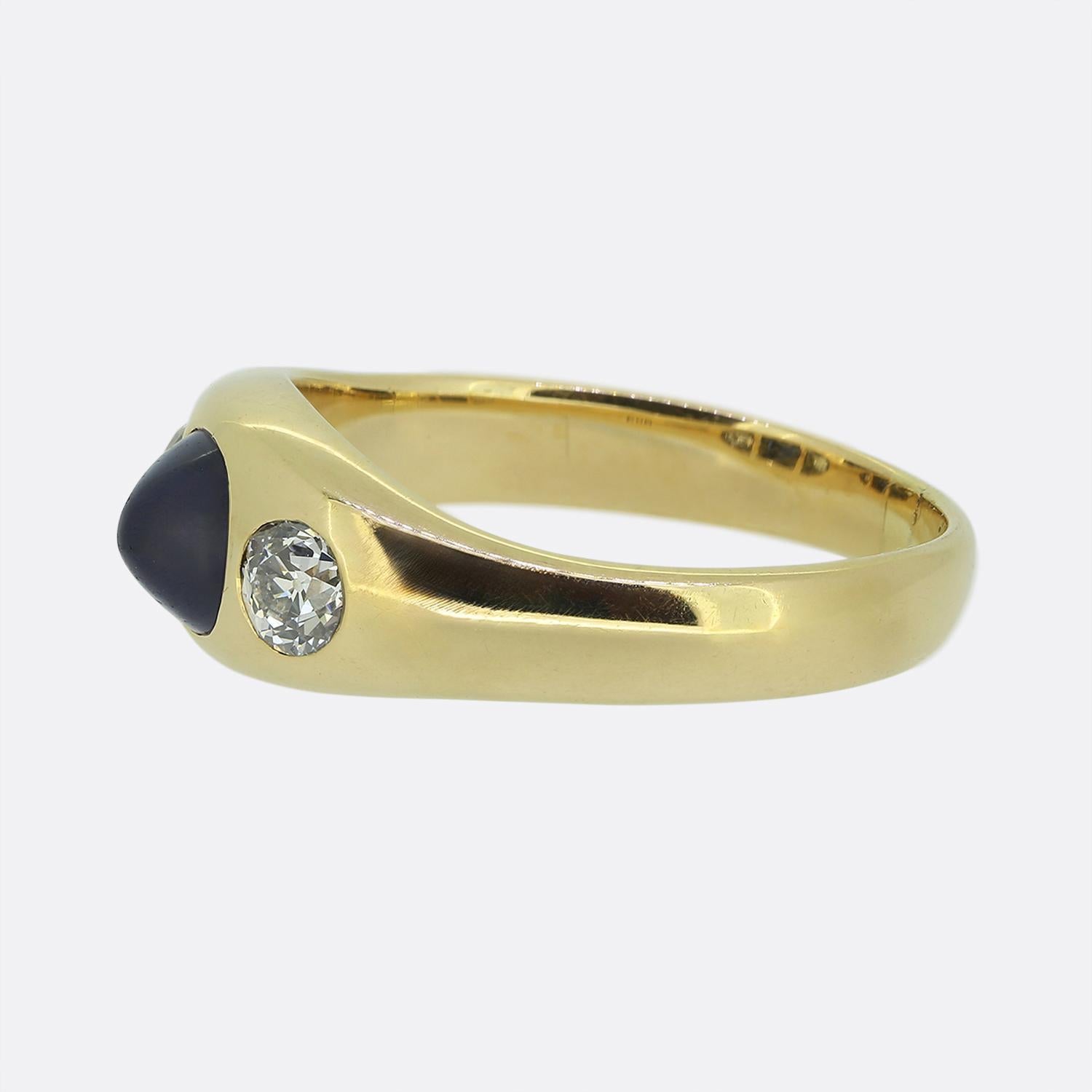 Ecco un favoloso anello a tre pietre con al centro un accattivante zaffiro blu con taglio a pan di zenzero, che emana una profonda e ricca tonalità di blu. Lo zaffiro è affiancato da due diamanti tagliati da una vecchia miniera, ognuno dei quali