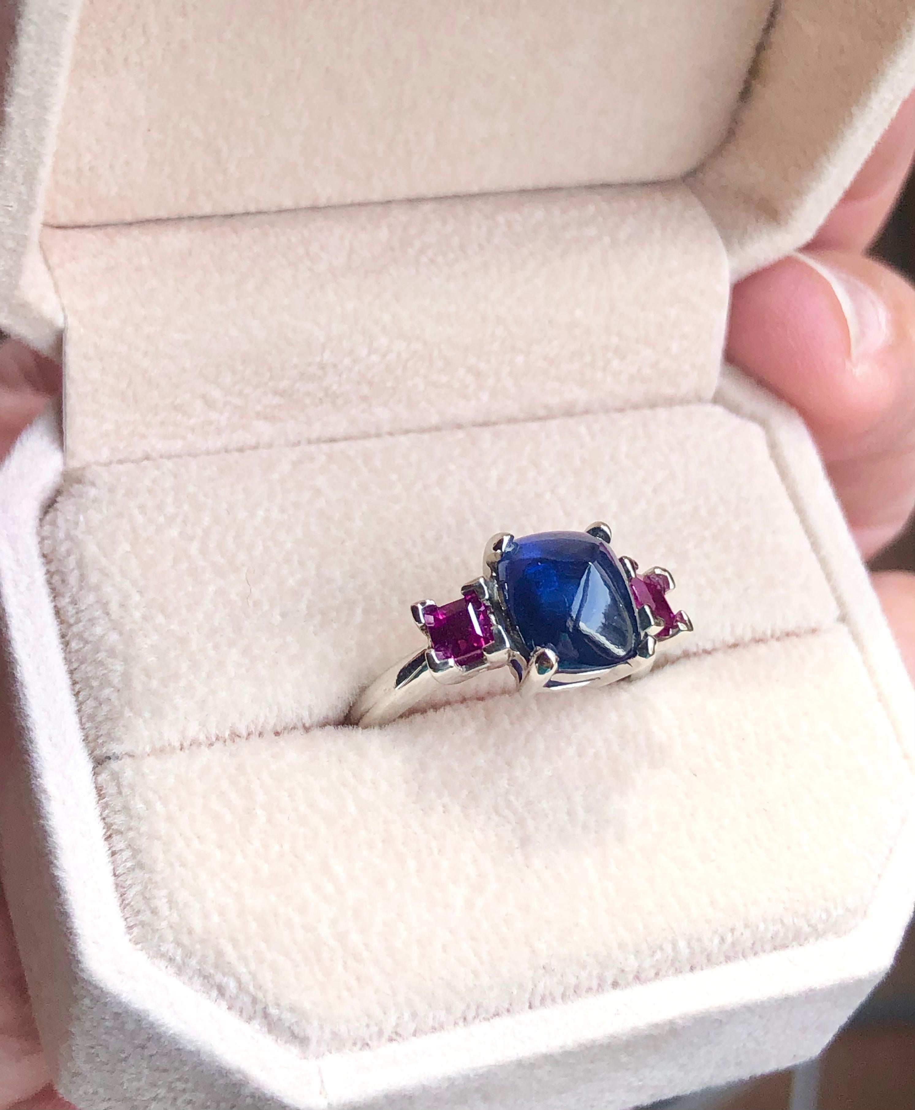 Featuring a sugarloaf cabochon sapphire weighing 3.88 carats, the side is framed by two stunning color and clarity natural rubies approx. weight approx. 1.00 carats. The classic three stone ring is elegant and sophisticate. 
Size 7 ensures a