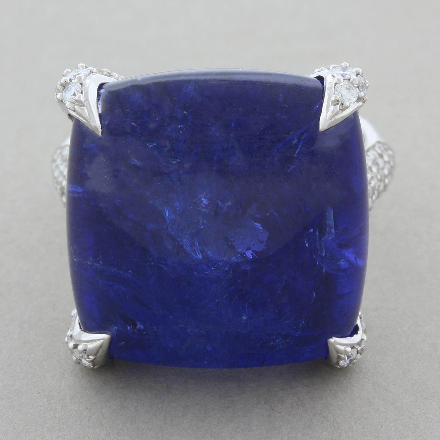 An exquisite ring featuring a 28.42 carat sugarloaf tanzanite with a deep purplish-blue color. The smooth tanzanite is accented by 3.20 carats of VS quality colorless diamonds wrapping around the shank and upwards onto the sexy claw prong settings.