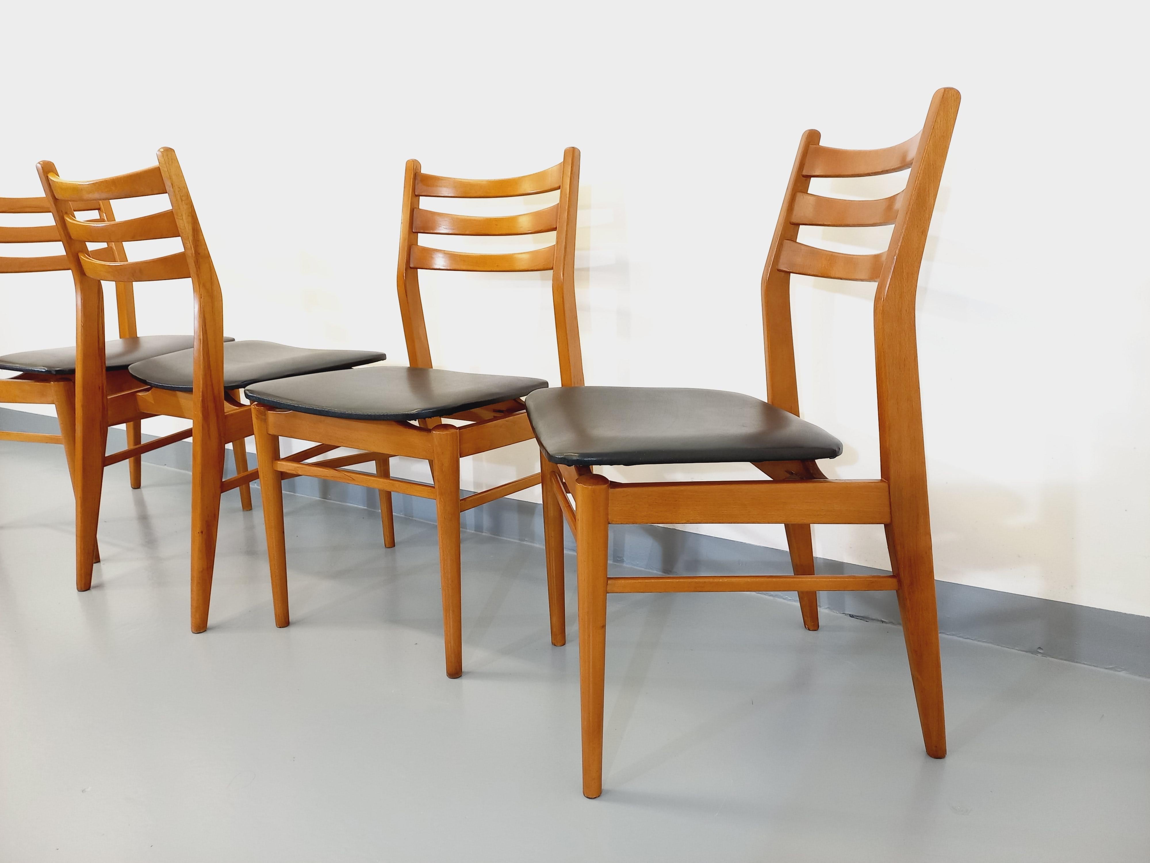 4 chaises style scandinave vintage des années 50 60, en bois style teck, dossiers à 3 barreaux horizontaux, assises en skai noir, pieds compas, très bon état général, skai en très bon état. 
Ref 230 606
Hauteur : 84 cm
Largeur : 45 cm
Profondeur :