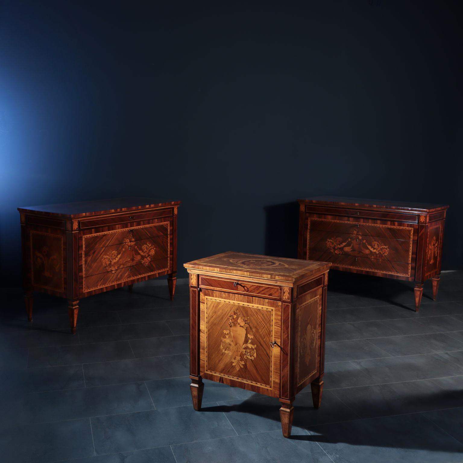 Coppia di cassettiere con quattro cassetti e un comodino con anta e cassetto sotto il piano. I mobili in noce massiccio sono impiallacciati principalmente in noce rigato con intarsi in vari legni, non tutti identificati, tra cui acero, bosso, acero