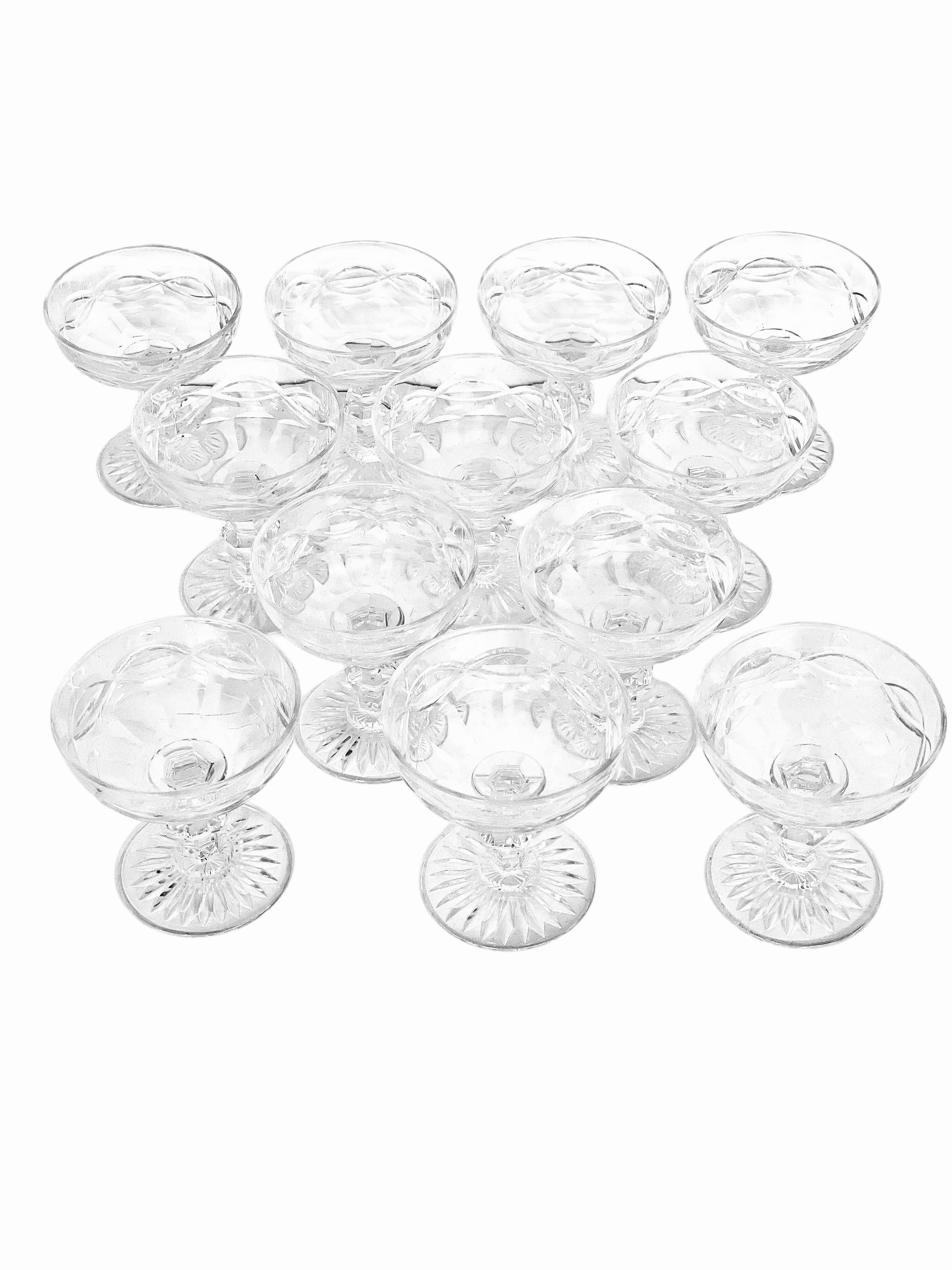 This exquisite set of 12 French crystal champagne coupes dates back to the 19th century and embodies timeless elegance and refined craftsmanship. Each coupe is delicately hand-cut with a graceful pattern of interlacing curves, adding subtle texture
