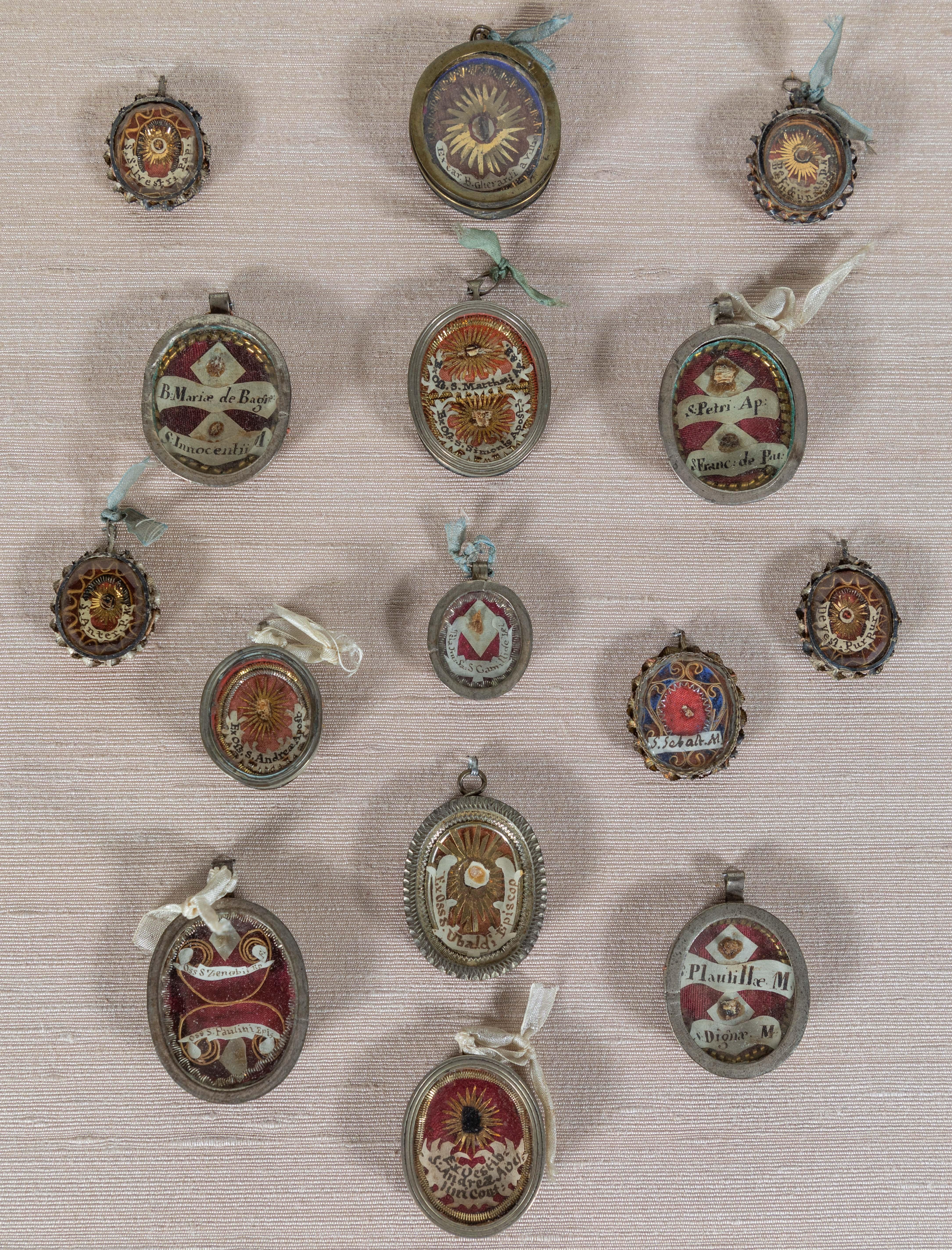A remarkable collection of 15, Italian, circa 1650, metal framed, wax-sealed, glass front reliquaries inset with fabric fragments amid gilt metal, and hand-written, ink-on-parchment labels.