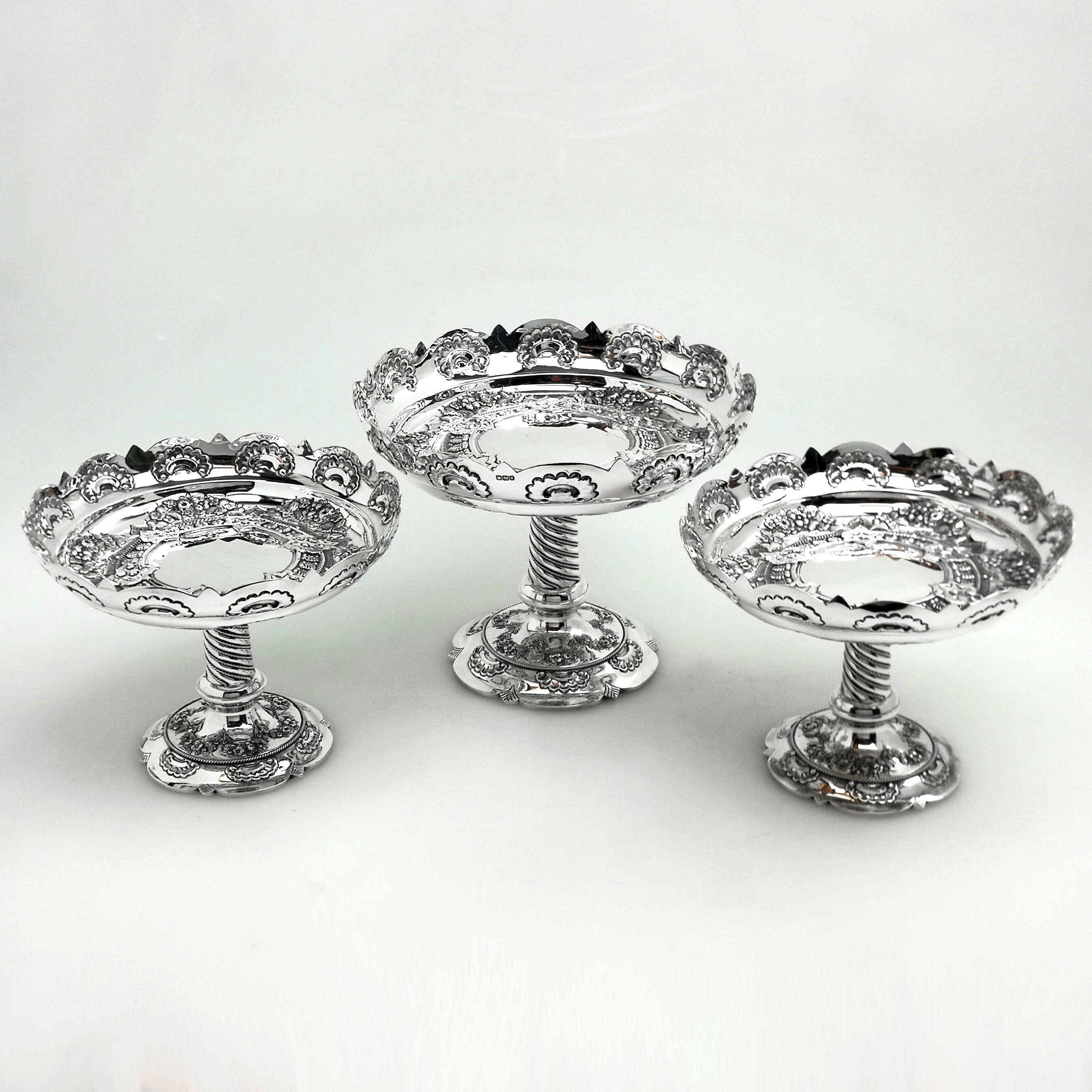 A lovely suite of 3 Antique Victorian solid Silver Comports / Dishes comprising of one large Dish and two matched smaller Dishes. This set of three Dishes has elegant flat chased bowls on tall chased columns on top of a spread pedestal foot.
 
 Made