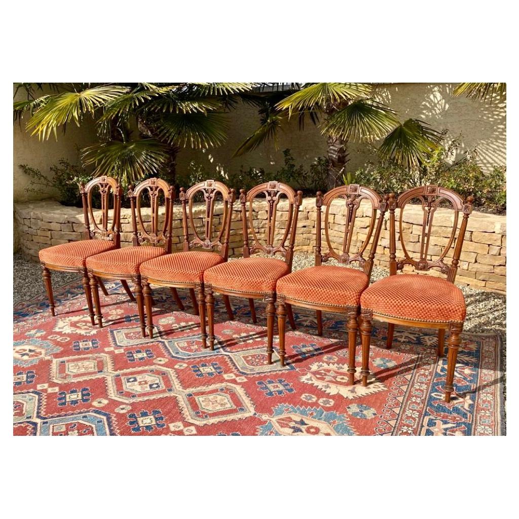 Suite of 6 Louis XVI style walnut chairs. Seats covered with an orange diamond fabric in very good condition and very nicely carved curved backrests. French work of good quality.