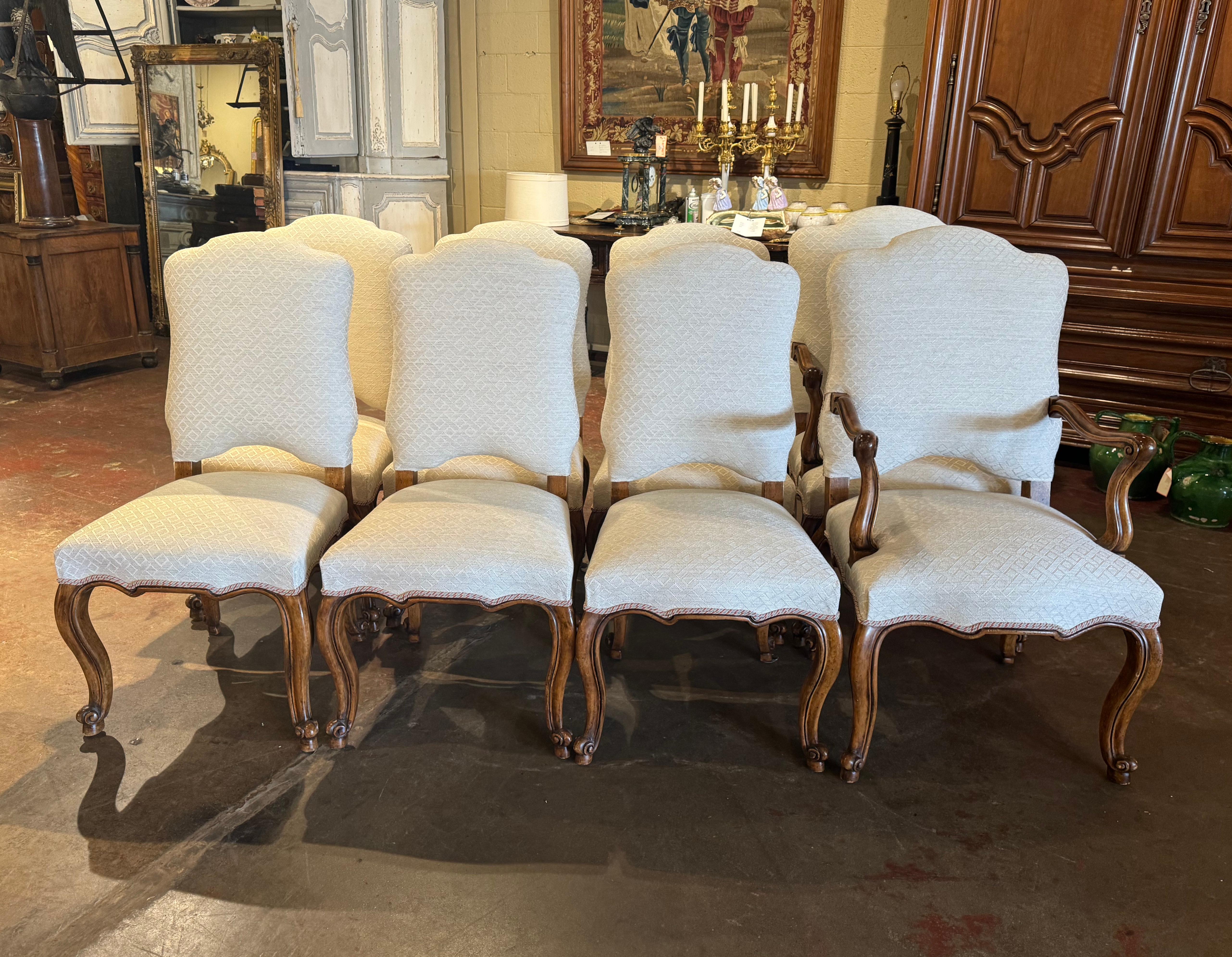 Dress a dining table with this elegant suite of six side chairs and matching armchairs. Crafted in France, circa 1980, each chair stands on cabriole legs ending with escargot feet, over a scalloped apron. The chair features a tall arched and pitched