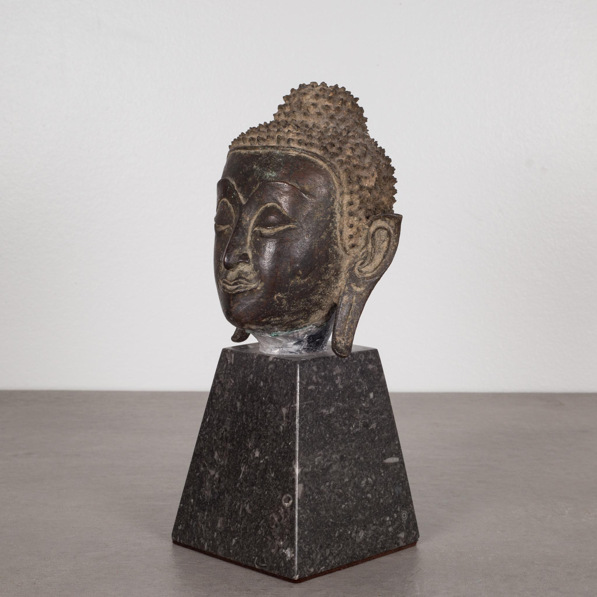 About:

This is an original lost-wax casting bronze head of Buddah Shakyamuni from the 19th century, Thailand. It is mounted on a contemporary marble base. His meditative expression, arched eyebrows, downcast eyes, smiling lips, elongated earlobes