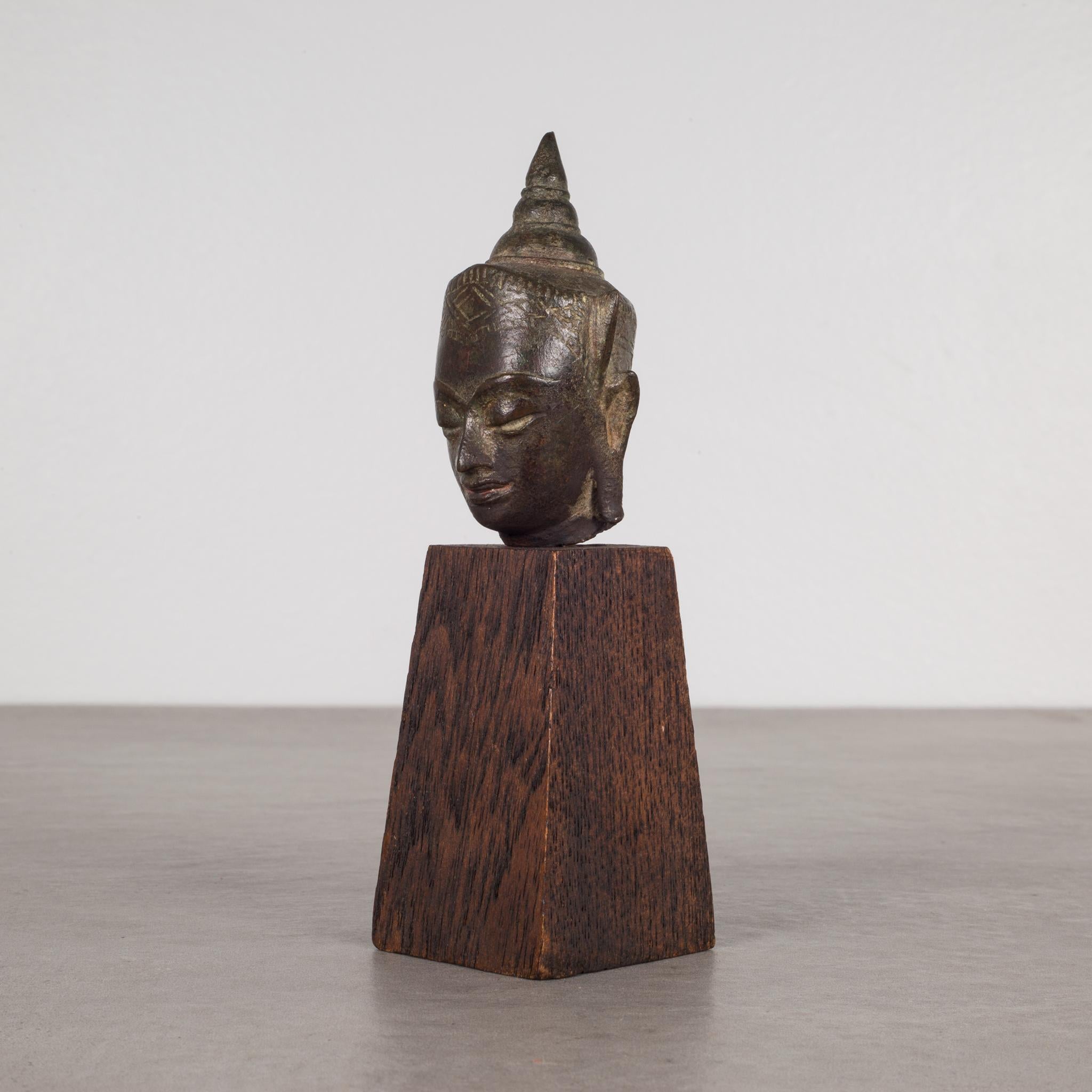 About:

This is an original lost-wax casting bronze head of Buddah Shakyamuni from the 19th century, Thailand. It is mounted on a contemporary wood base. His meditative expression, arched eyebrows, downcast eyes, smiling lips, elongated earlobes