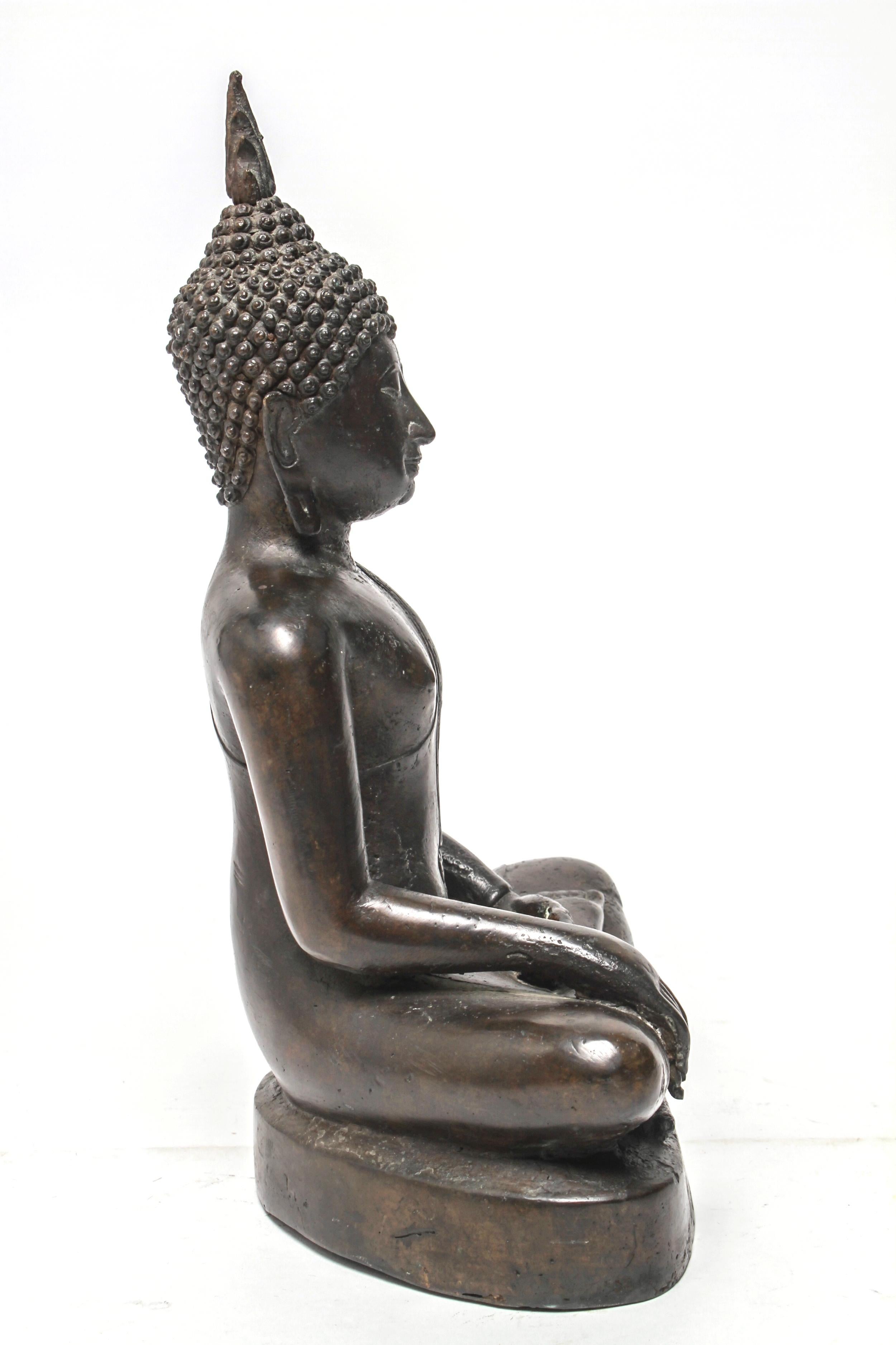 Sukothai style Thai patinated bronze seated Buddha sculpture with downcast eyes, flaming ushnisha, and elongated ears, depicted in Bhumisparsha mudra. The piece is in great vintage condition with a desirable age-appropriate patina.