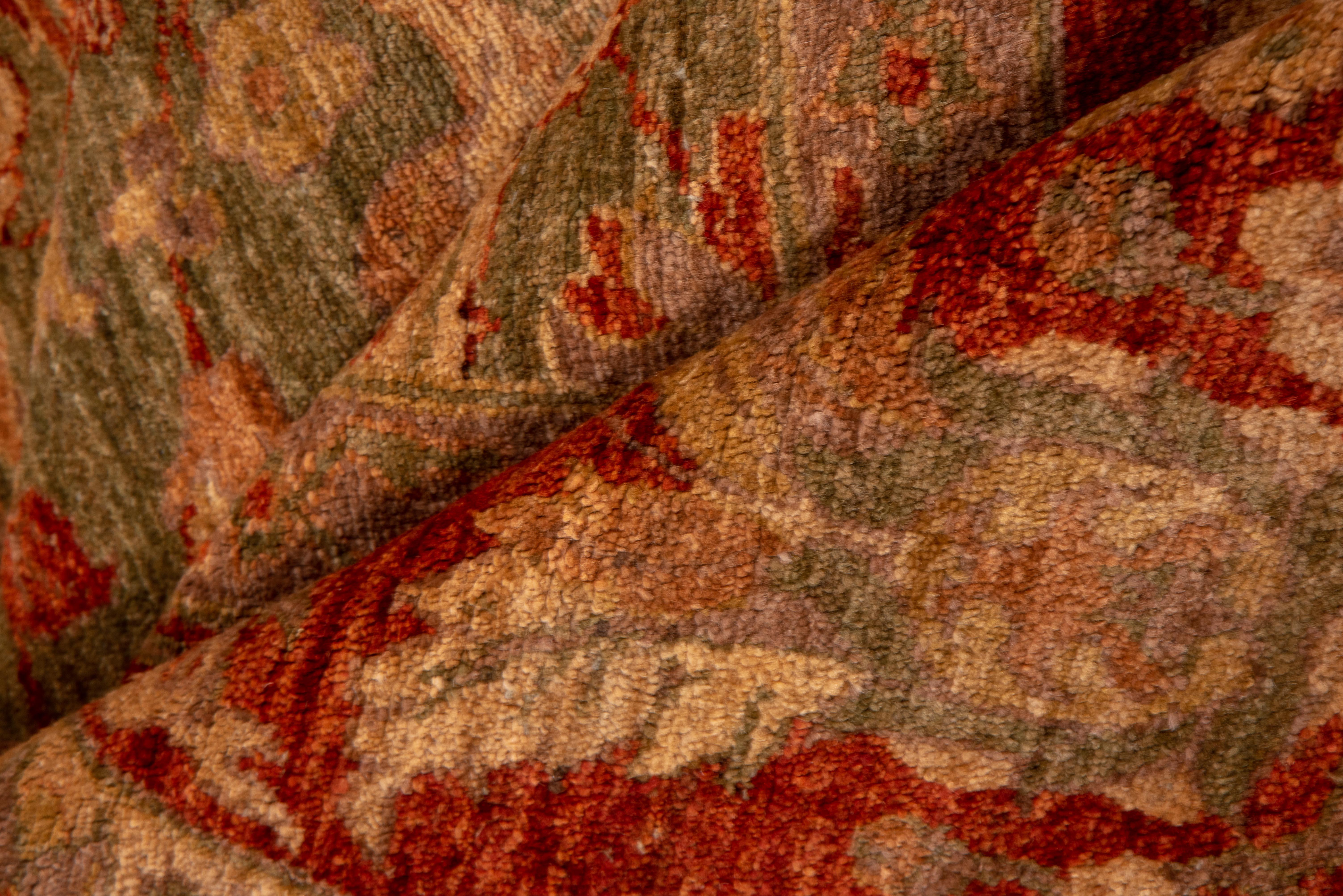 This vintage Sultanabad rug makes a bold impression with its richly saturated moss green field enlivened by scrolling palmettes, rosettes, and floral flourishes in tones of rust, soft gold, and terra cotta. The composition is symmetrical and