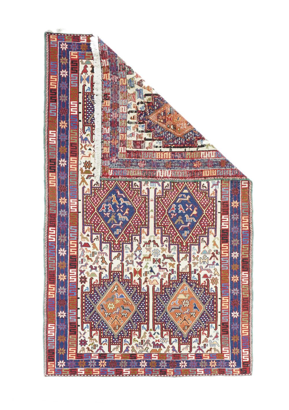 Alfombra Sumak 3'10'' x 6'7''. El fondo de marfil está decorado principalmente con dos columnas de tres polígonos ganchudos y escalonados cada una, con rombos de color óxido o azul en su interior. Los pequeños pájaros y animales proporcionan el