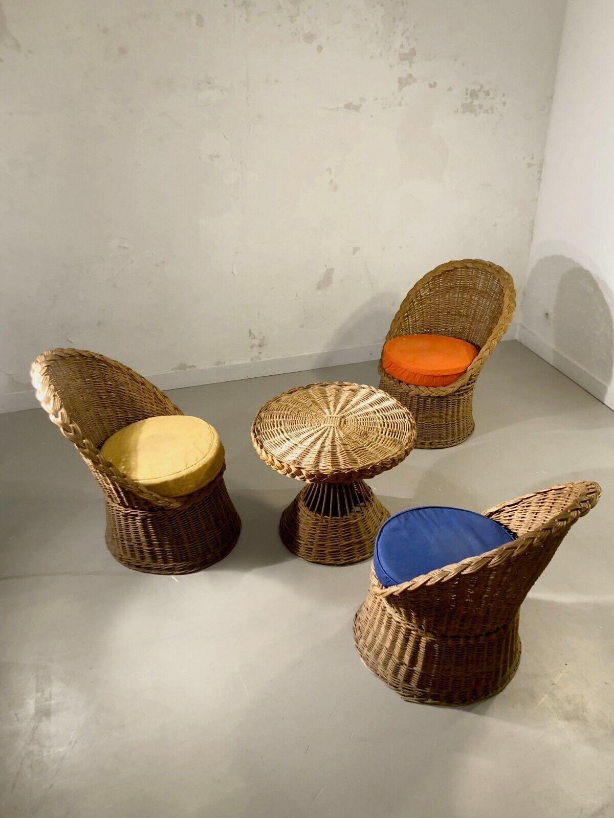 A small summer lounge for a terrace, Modernist, Free Form, Reconstruction, including 3 armchairs in woven rattan with original circular seats in primary colors red, blue, yellow, and a small openwork diabolo table in woven rattan, to be attributed,