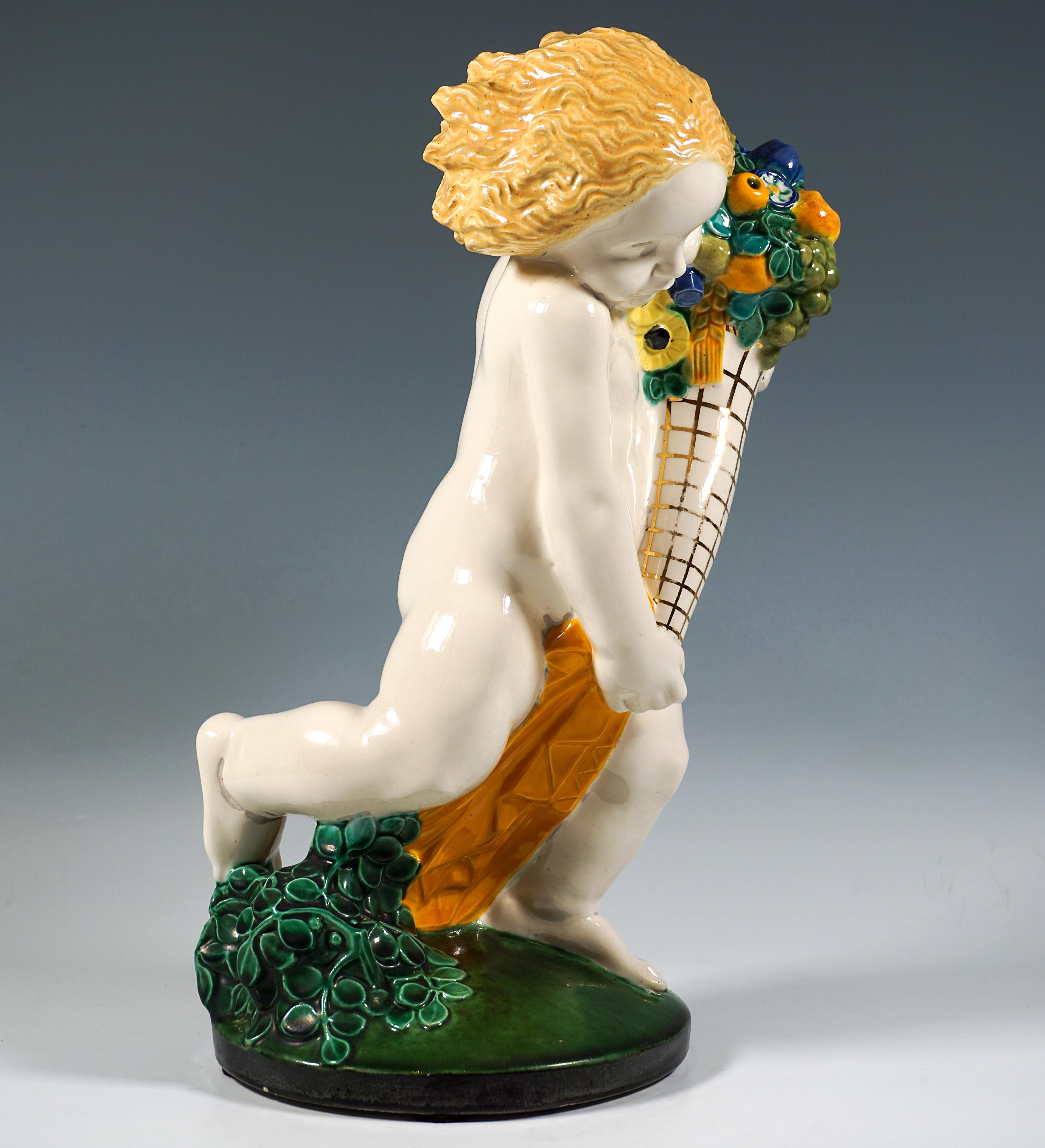 Excellent and very rare Art Nouveau ceramic piece from a series of the four seasons:
Running nude putto with flowing blond hair, a drapery around his front thigh and holding a cornucopia full of flowers and fruit in front of him with both hands.
The