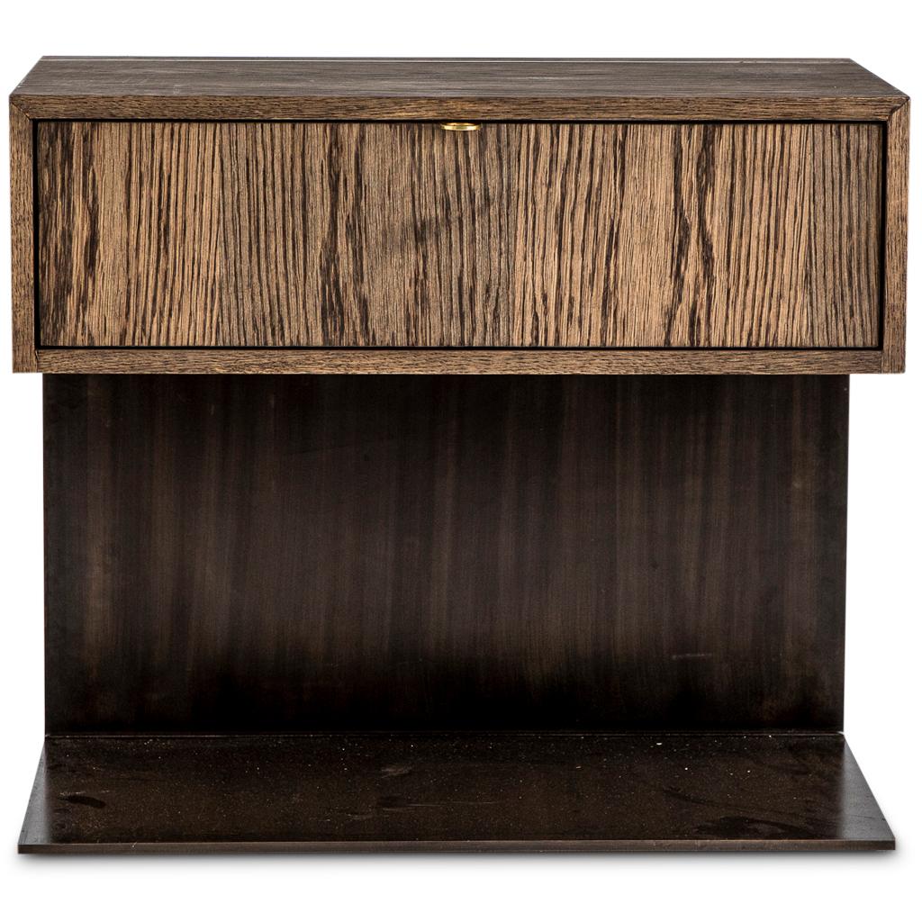 Der moderne Nachttisch Hawkstone steht auf einem handgemeißelten, schwarz brünierten Sockel aus fremdem Holz. Auf dem Sockel befindet sich ein Schubladenelement aus geräucherter Eiche mit Soft-Close-Scharnieren. Die Schublade hat einen Griff aus