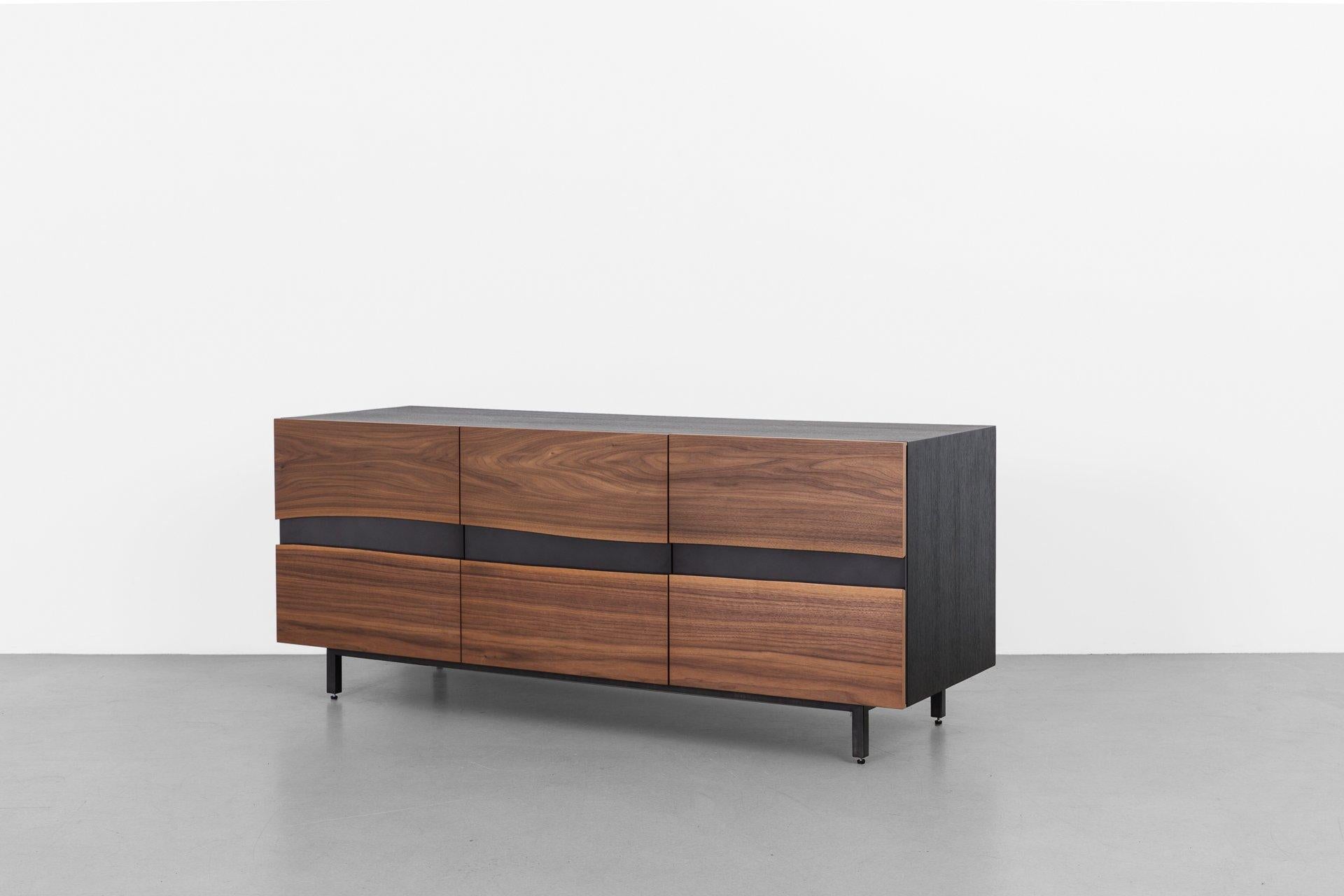 Our Summit credenza features two facing walnut live edges mounted on aluminum doors that create its dynamic front. Three seamless doors open to adjustable interior shelving, allowing for custom storage arrangements. The surrounding frame is finished