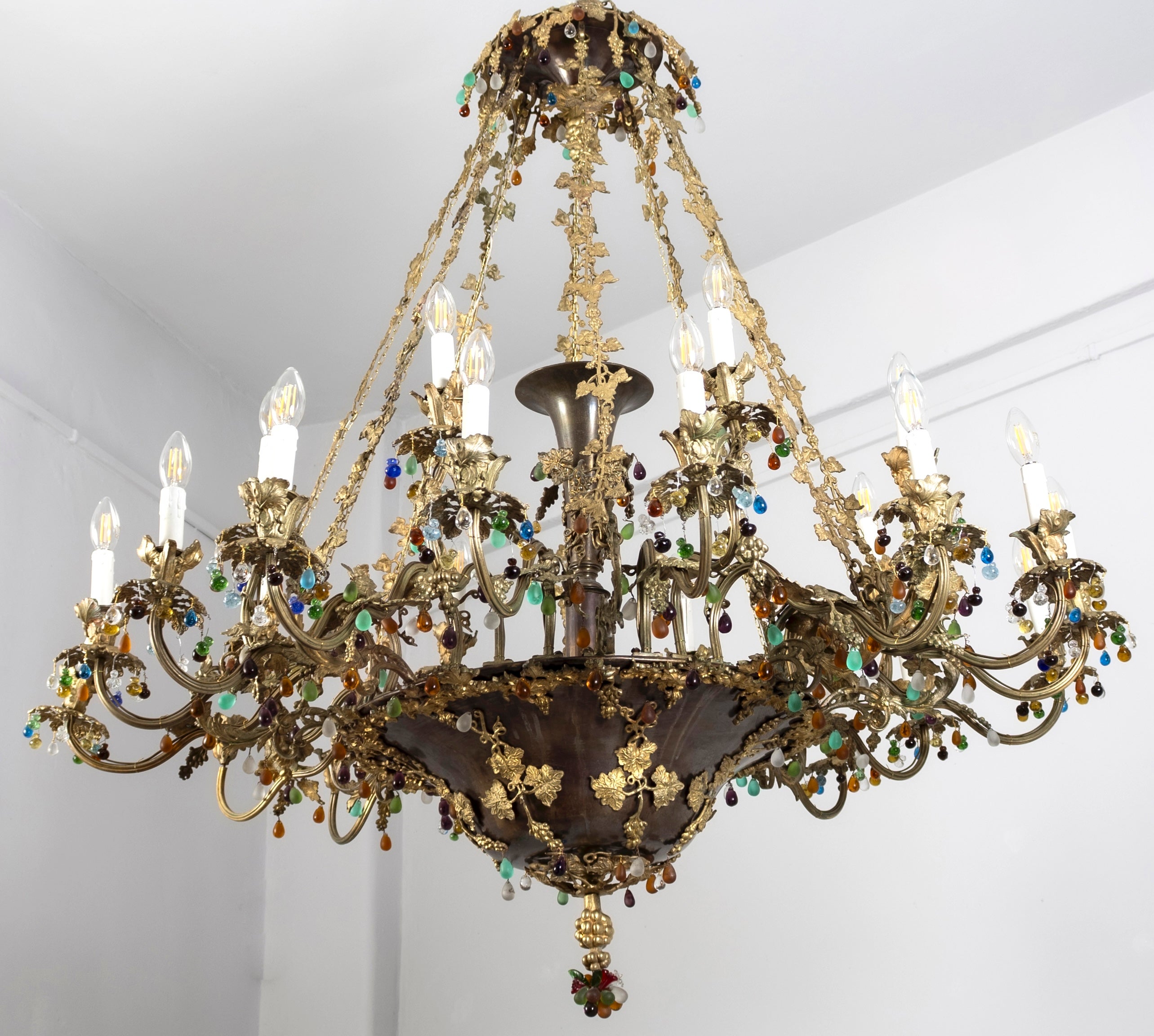Herausragend  Vierundzwanzigarmiger Kronleuchter aus brünierter und vergoldeter Bronze  mit fein gemeißelten  Reben und Blätter.
Dekoriert mit einer Reihe von kostbaren mehrfarbigen geschliffenen Kristallen und Tropfen.
Ideal für einen großen