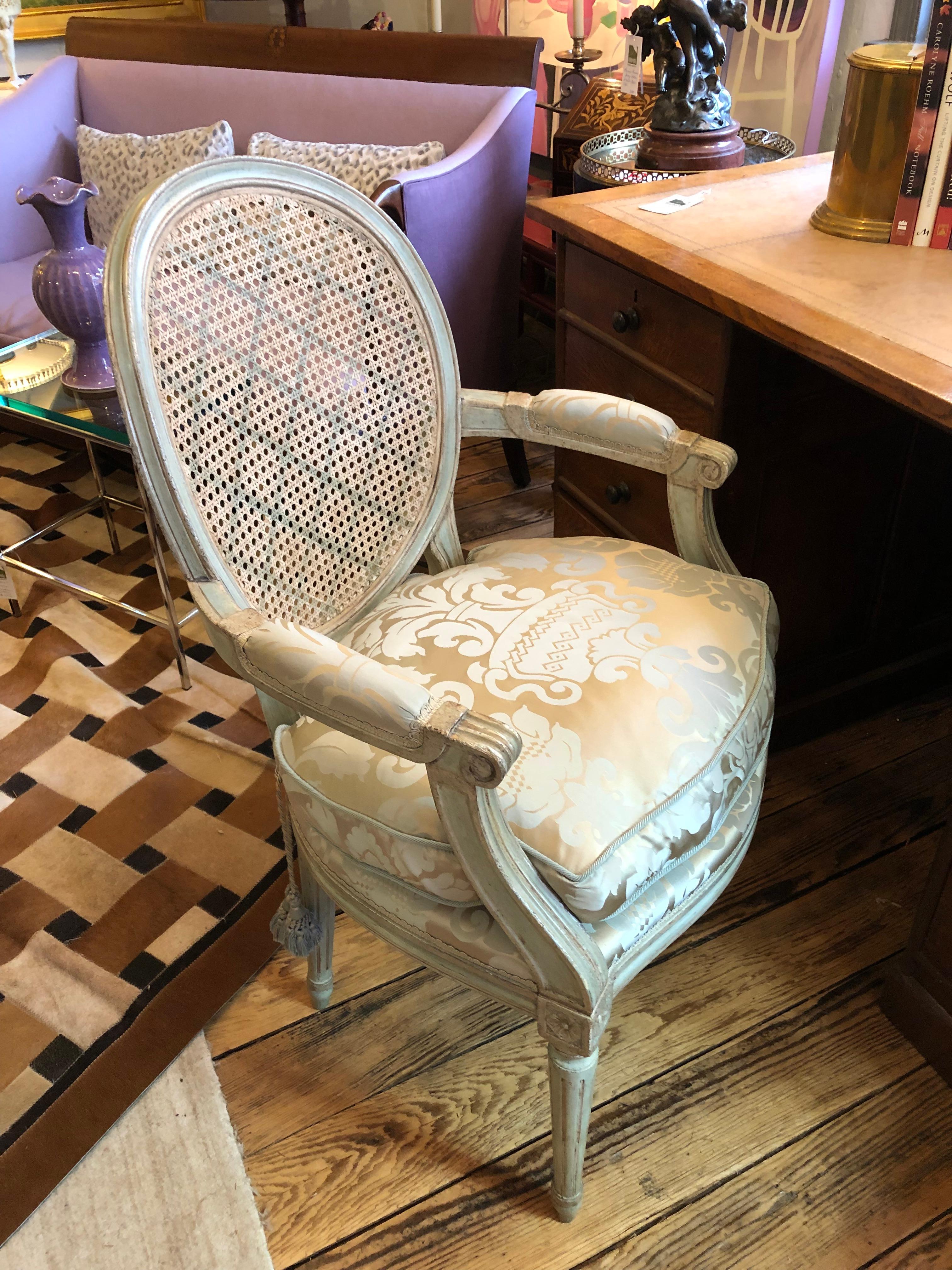 Glamorous celadon painted arm chair having silver gilt embellishment with classic French fauteuil shape and carving. The back is caned and painted with a subtle criss cross decoration, and the seat upholstery with down cushion are fit for a Princess