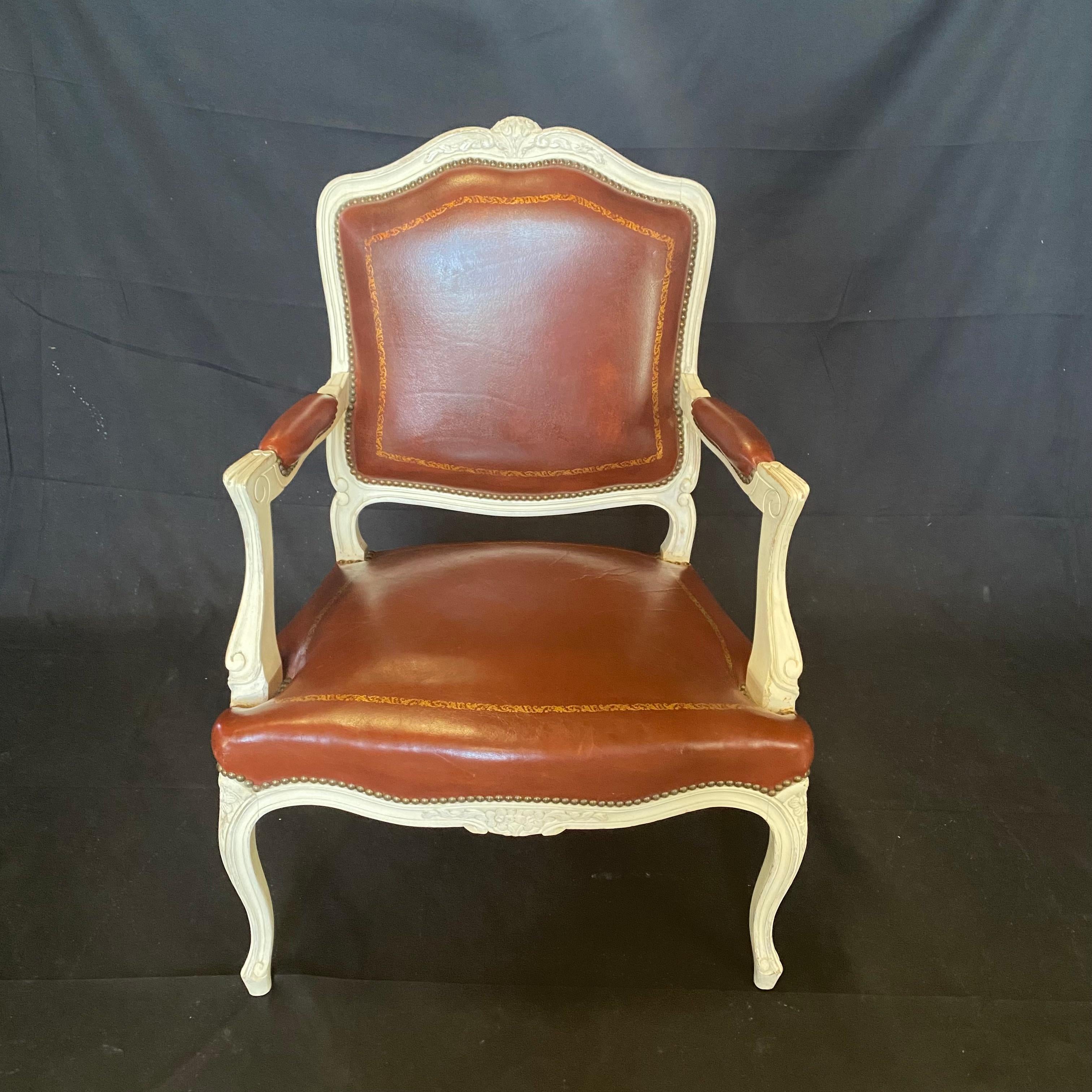 Stunning Set of Seven French Louis XV Leather Embossed Armchairs or Fauteuils, to be used in any room of the home. Can be used as elegant dining chairs, or armchairs in the living or sitting room or study. Ivory painted carved walnut provides a