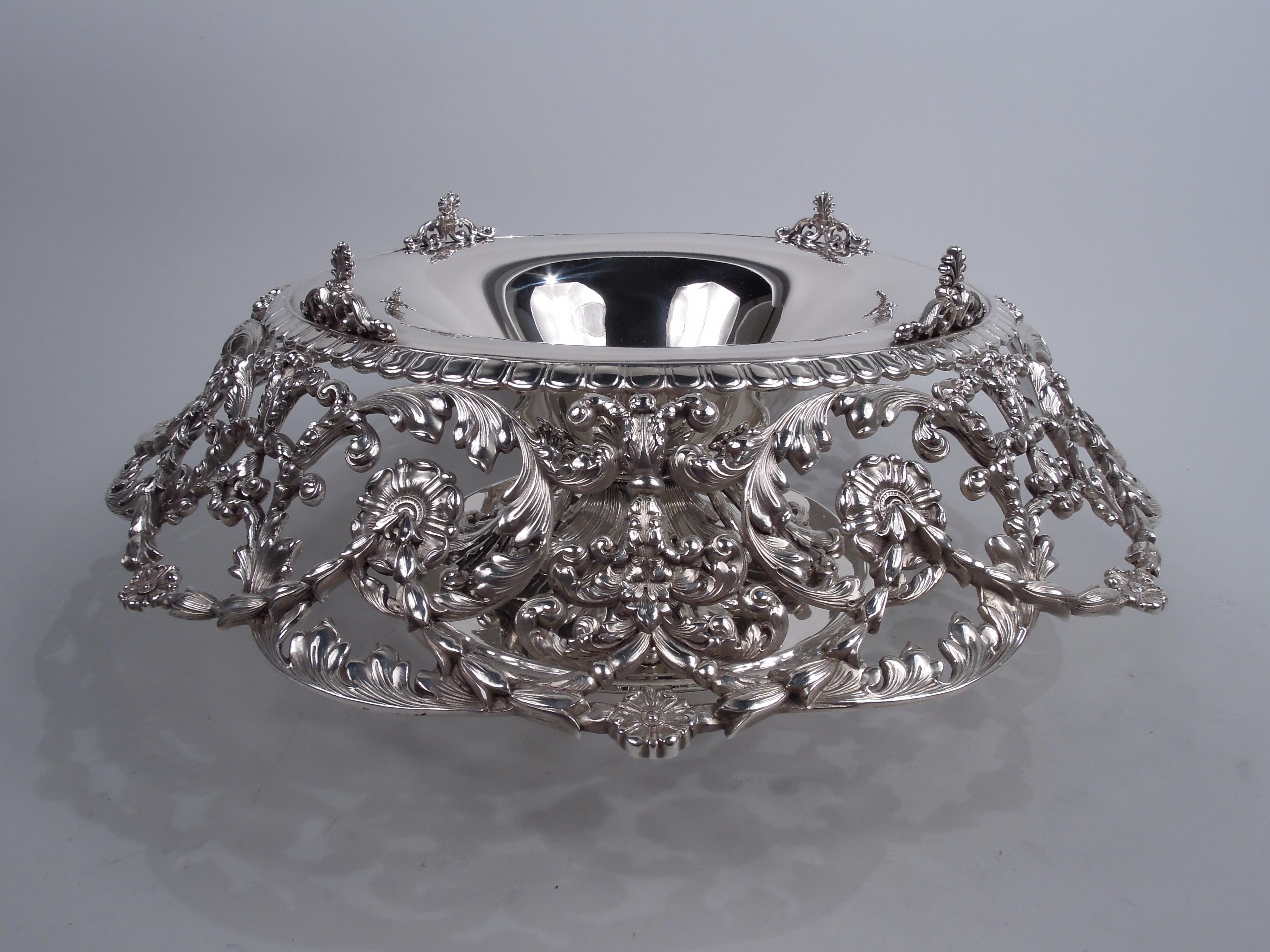 Edwardian Classical sterling silver centerpiece. Made by Tiffany & Co. in New York. Round and plain bowl; engraved egg and dart rim mounted with four scroll-mounted acanthus leaves. Large turned-down cast open rinceaux collar. Domed open cast leaf