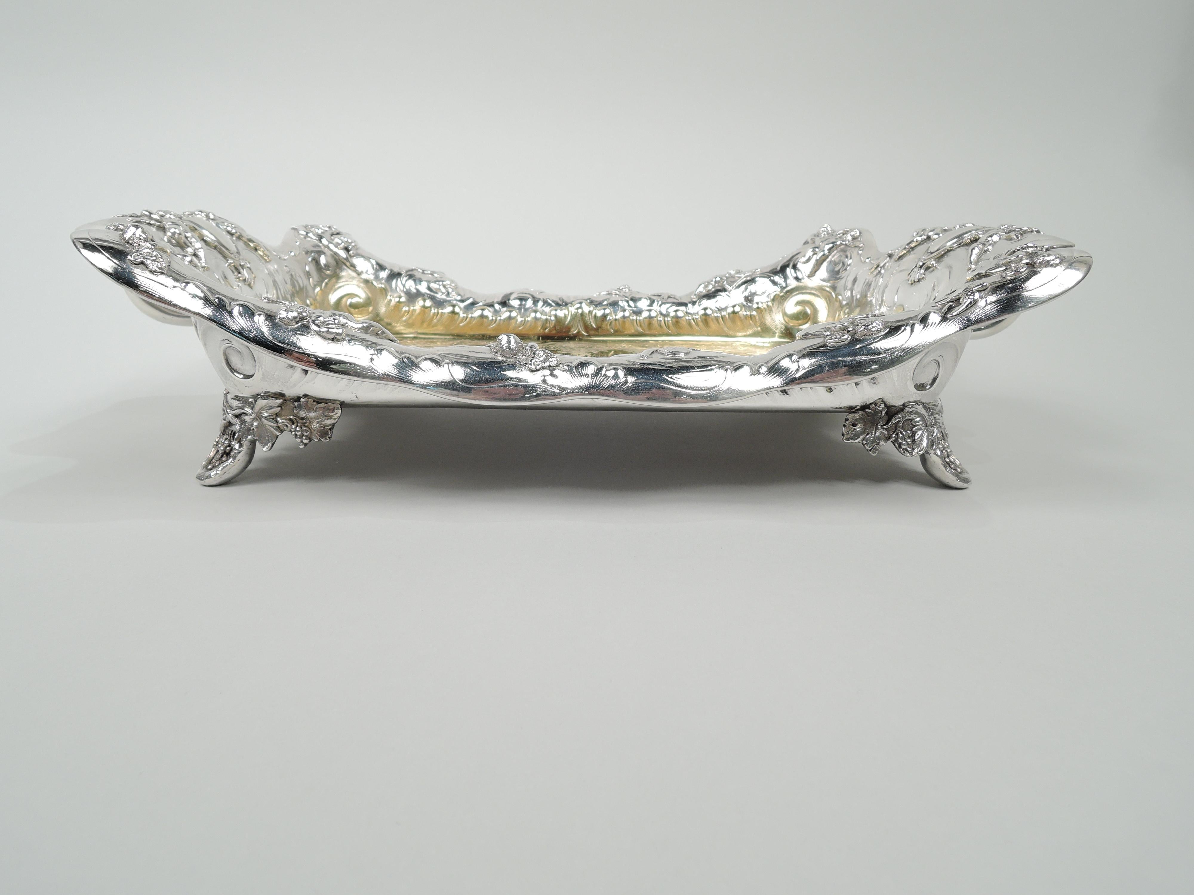 Sumptuous Victorian Classical sterling silver serving dish. Made by Tiffany & Co. in New York. Rectangular well and scrolling, asymmetrical turned-down rim; bracket-shaped ends with leaf-mounted scroll handles, and corner fruiting grapevine