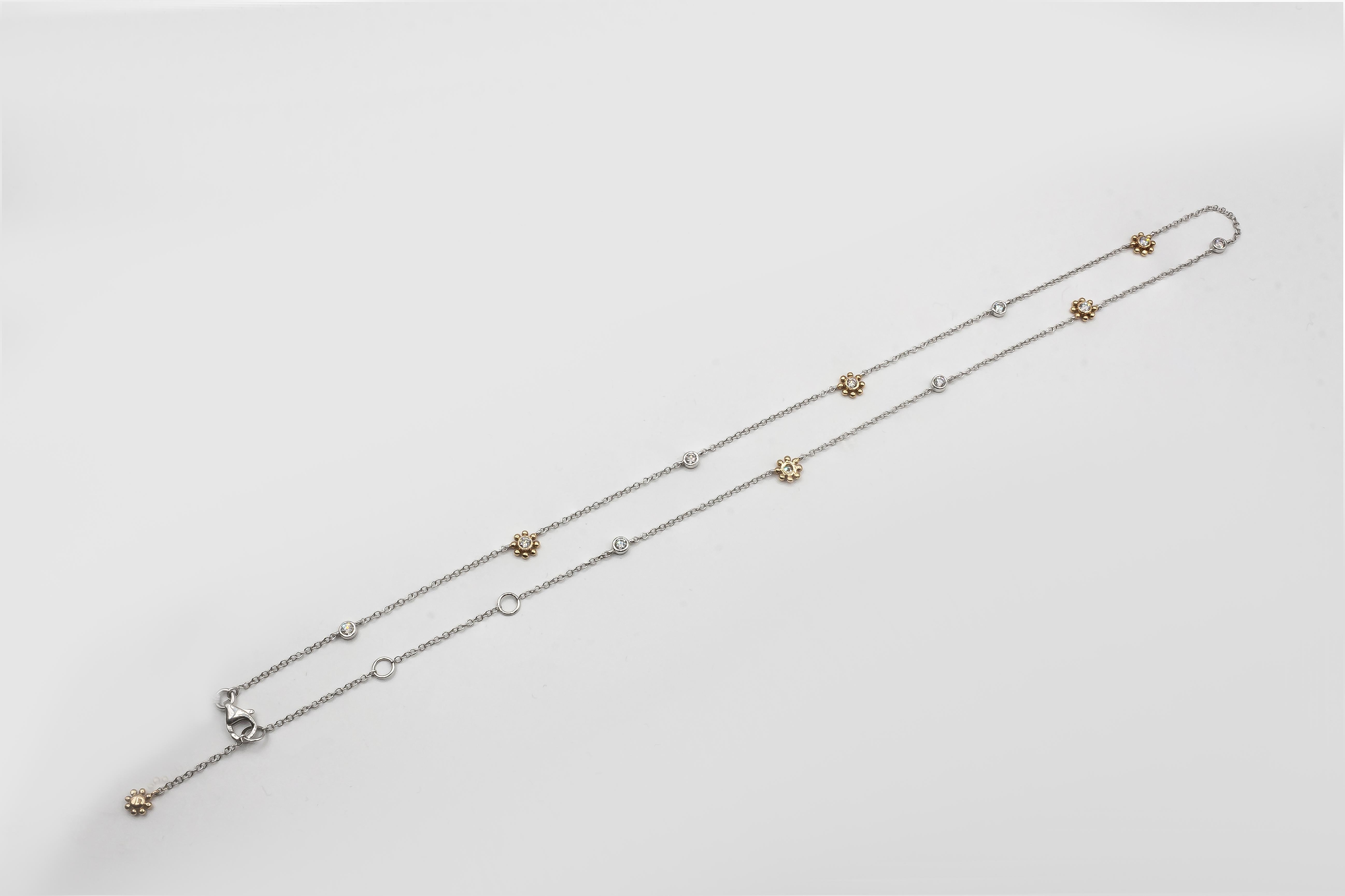 A fashionable necklace, showcasing round brilliant cut diamonds weighing 0.52 carat total, set evenly in a diamonds by the yard style. Diamonds are bezel-set in 18K white gold and 18K yellow gold with a sun motif in alternating fashion. Adjustable