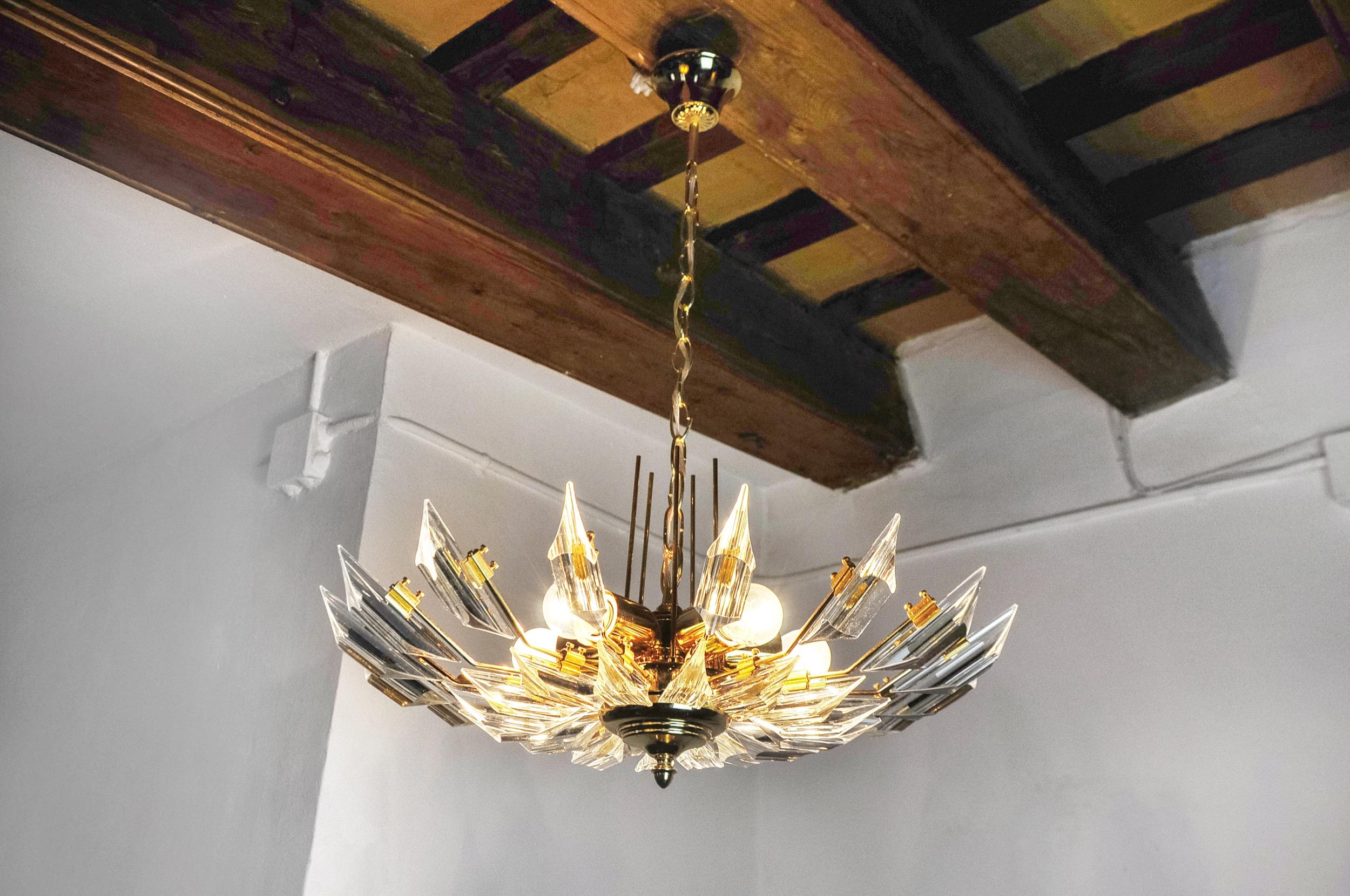 Superb and rare Oscar Torlasco sun chandelier designed and produced in Italy in the 1970s. This unique object is composed of cut crystals called triedri and a golden structure. Object that will illuminate wonderfully and bring a real design touch to