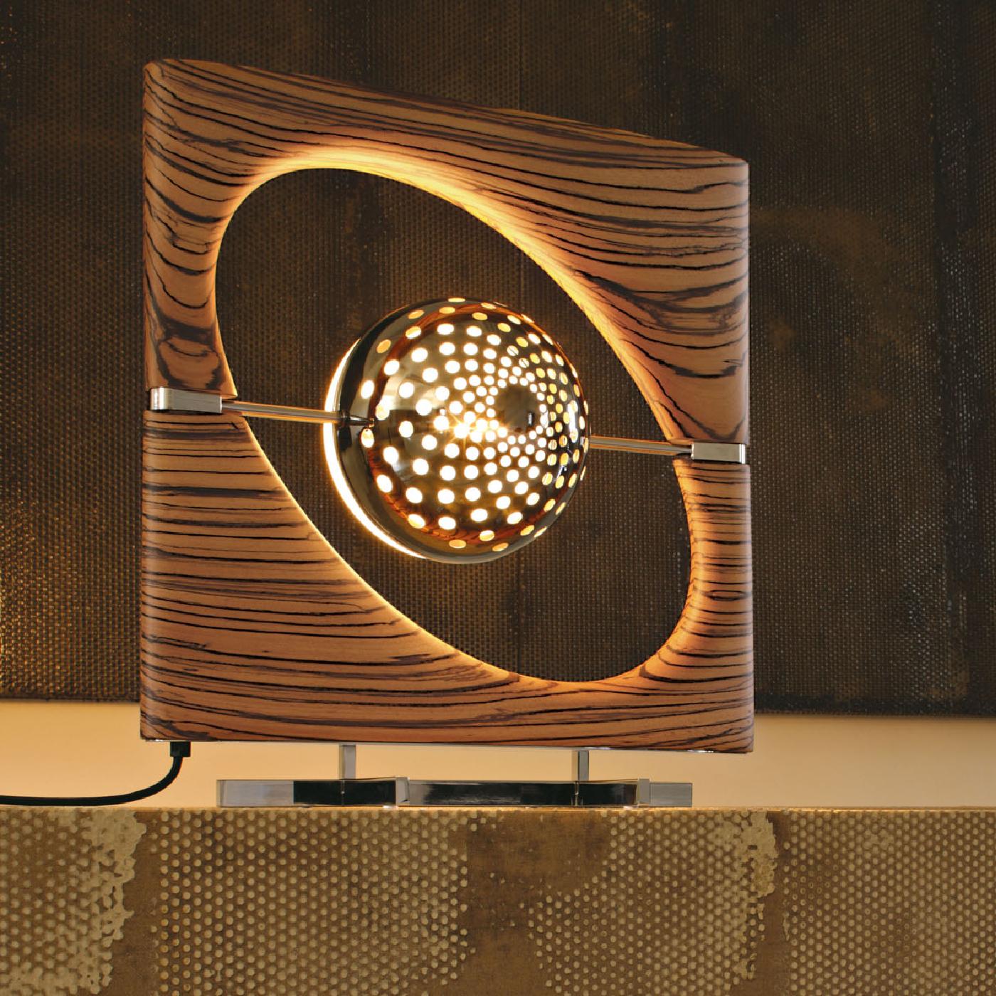 Each exquisite Sun Ra Zebrano table lamp features a frame of unique and decorative wood surrounding the chromium/brass plated and moulded acified white glass illuminating body in the center. The varying stripe patterns or small cracks and holes are
