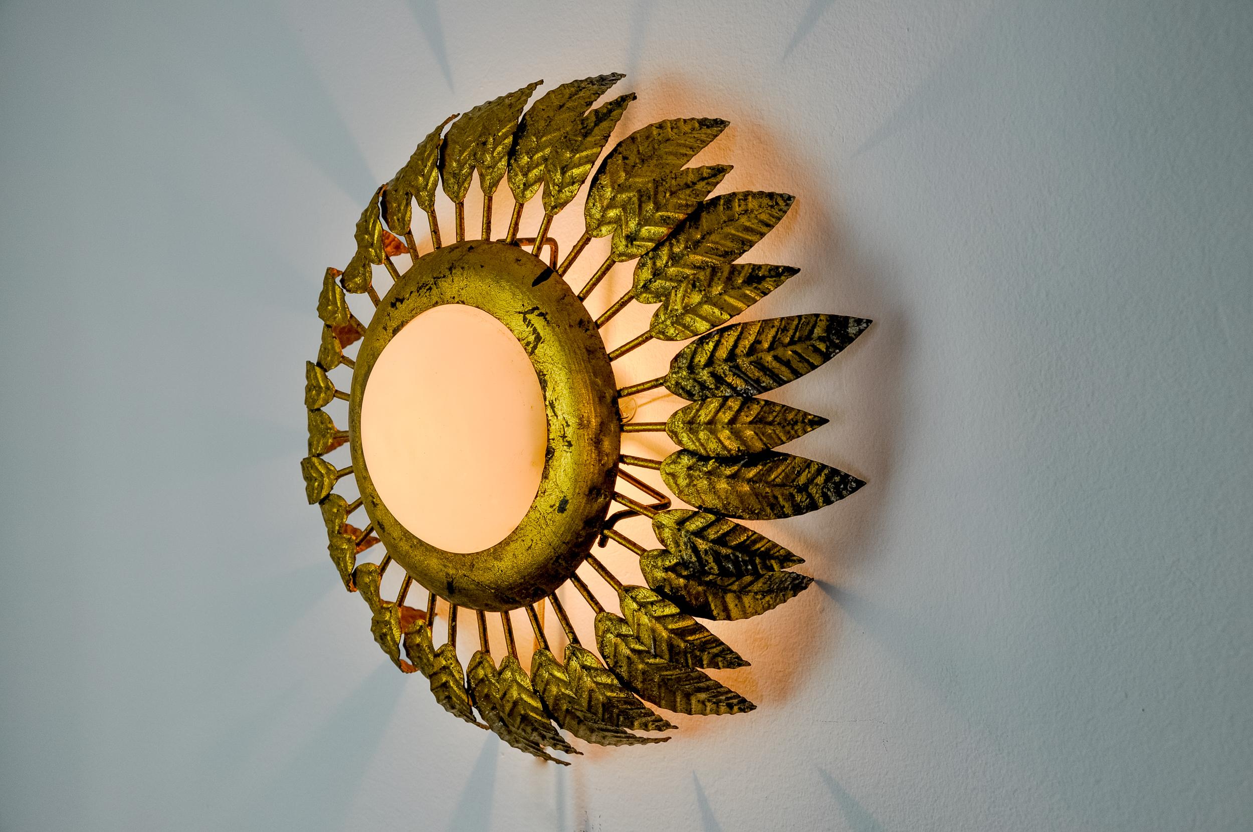 Sehr schöne und seltene Sonnen-Wandleuchte, entworfen und hergestellt von Ferro Arte in Spanien in den 1960er Jahren. Struktur aus blattvergoldetem Metall mit floralen Motiven, Opalglas. Einzigartiges Objekt, das wunderbar leuchtet und Ihrem