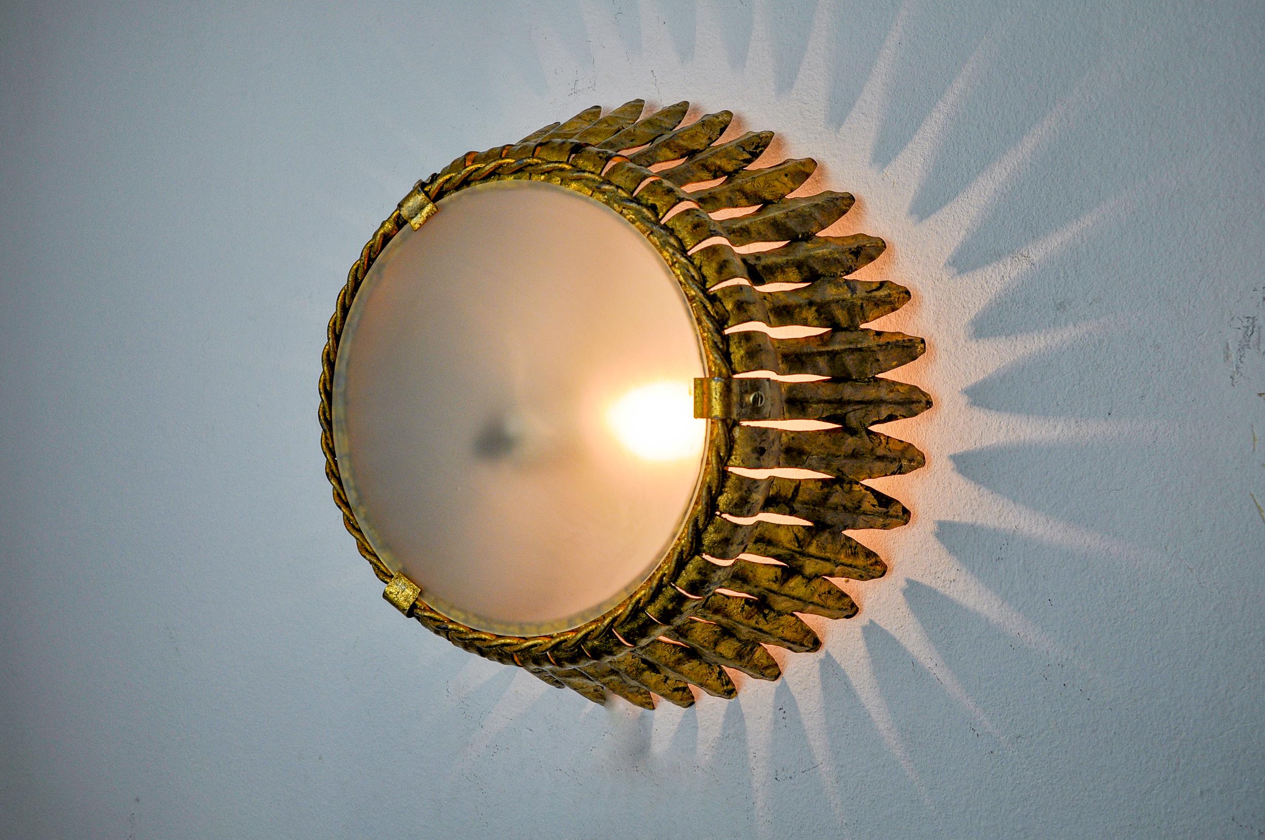 Grande et rare applique solaire, conçue et produite par Ferro Arte en Espagne dans les années 1960. Structure métallique dorée à la feuille d'or. Objet unique qui illuminera à merveille et apportera une véritable touche design à votre intérieur.