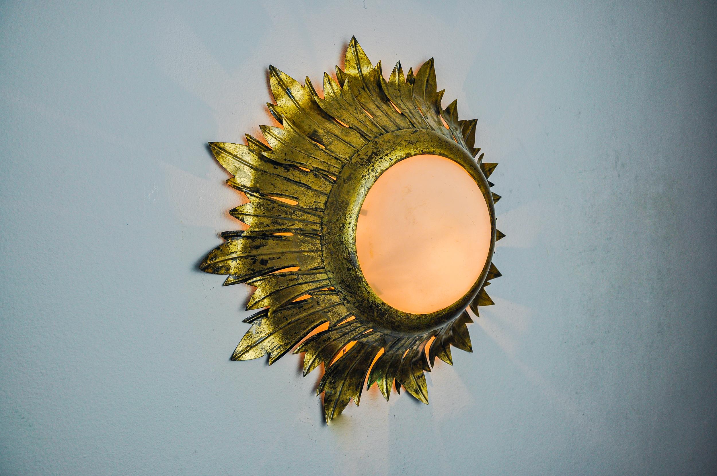 Très belle et grande applique solaire, conçue et produite par Ferro Arte en Espagne dans les années 1960. Structure en métal doré à la feuille et verre opalin. Des objets uniques qui s'illuminent à merveille et apportent une véritable touche design