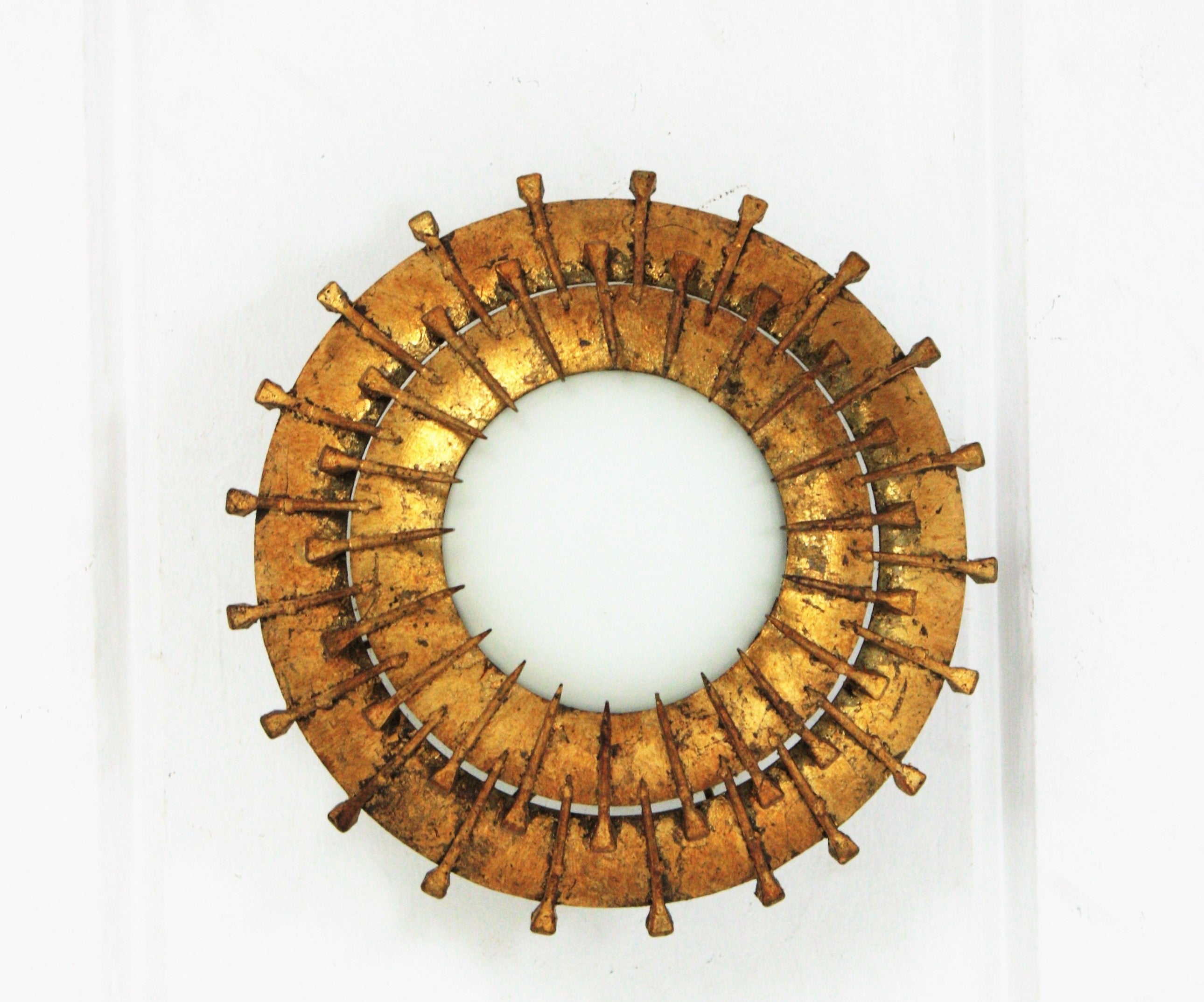 Double Layered Nail Design sunburst light fixture, milk glass, gilt iron, France, 1940s-1950s. 
This sunburst light fixture features a gilt iron ring with two layers of iron nails surrounding a central milk glass difusser. Style in transition from