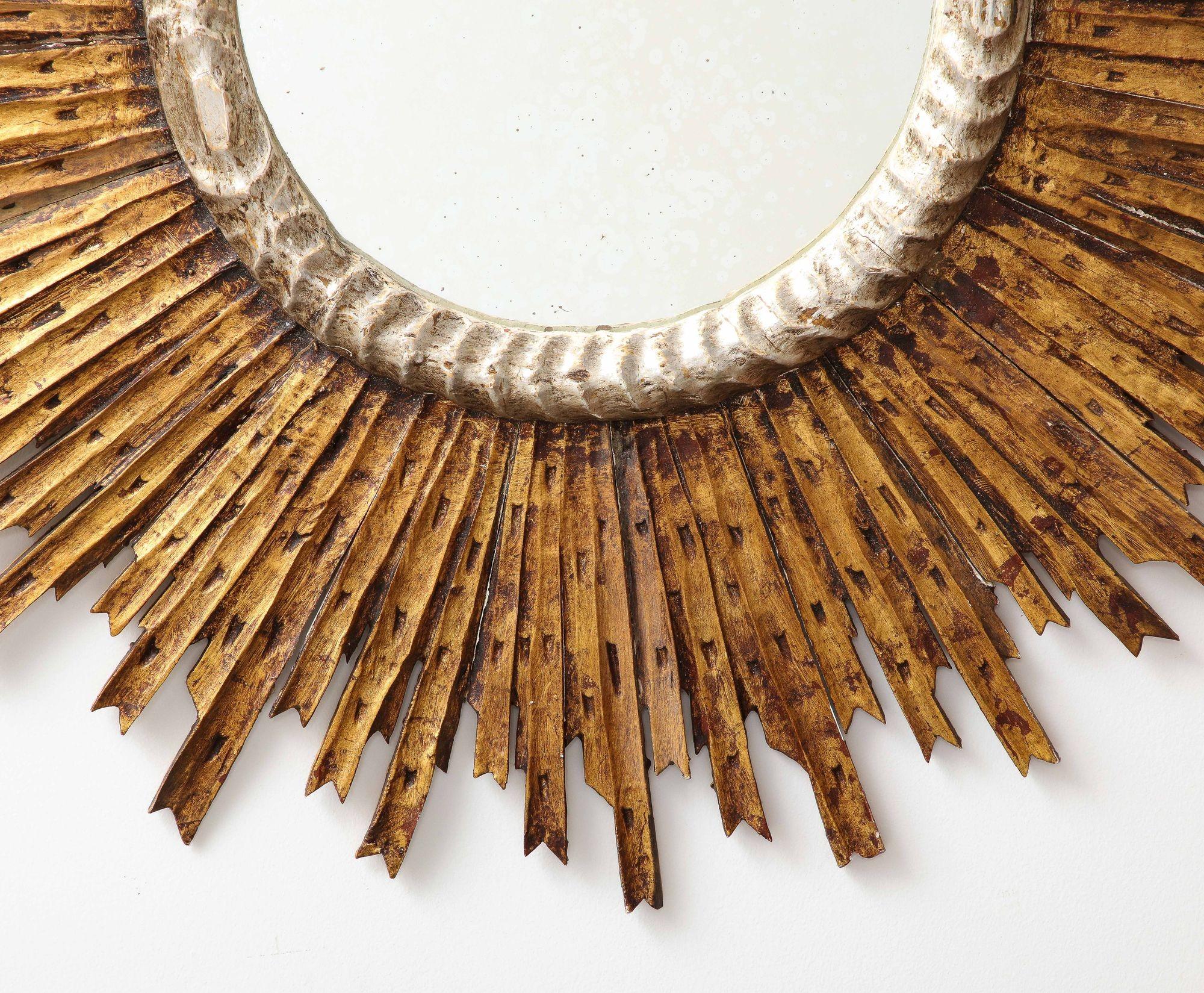 An exquisite classic Sunburst mirror, featuring a gold wood frame adorned with an inner silver rim, hailing from the mid 20th century. This striking piece offers a captivating visual centerpiece, with its radiating beams extending outwards from the