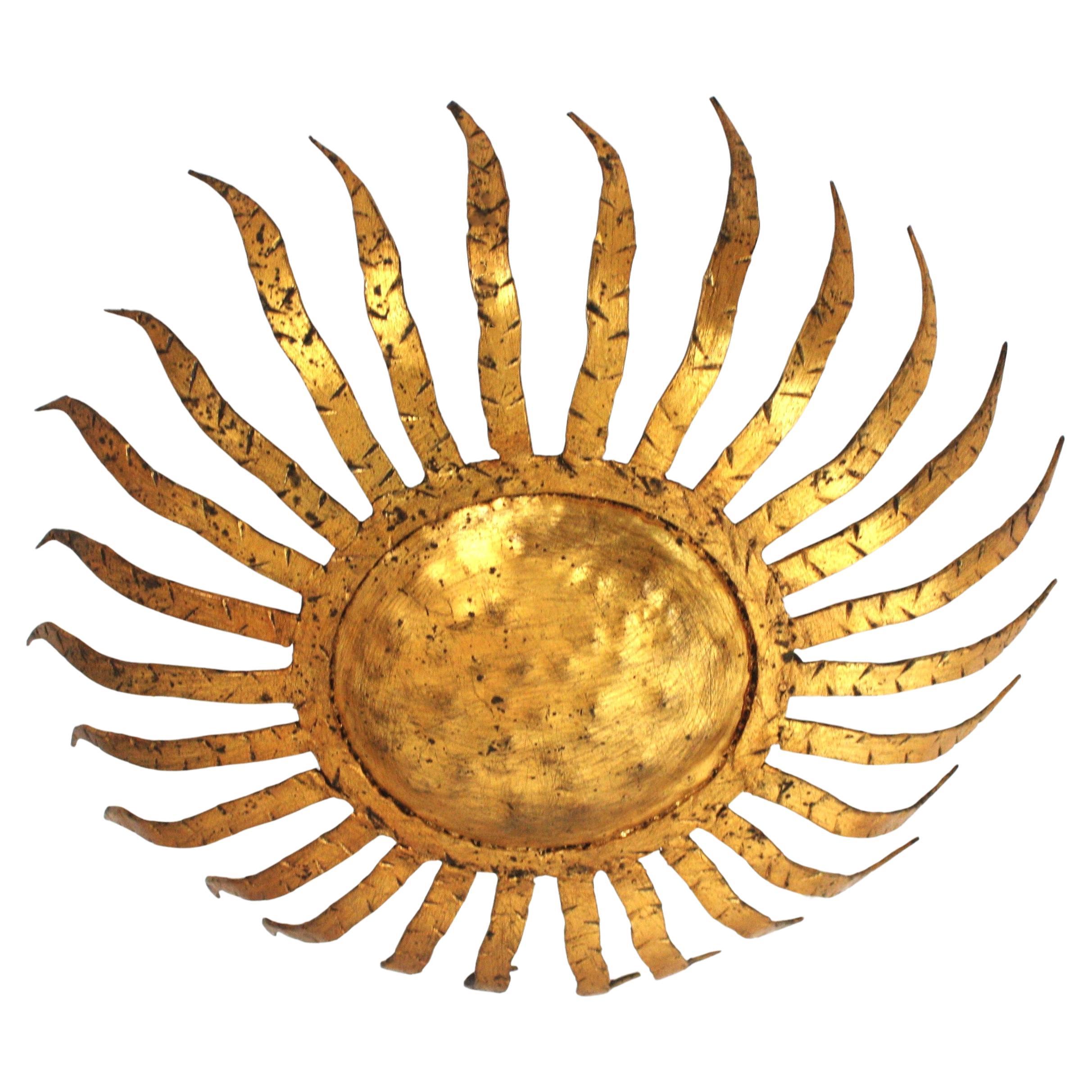 Spanish Hand Forged Sunburst Flush Mount in Gilt Iron, 1950s
Hand-hammered sunburst light fixture with thick rays. Richly adorned by the hammer marks thorough.  Slightly curly iron rays surrounding the central sphere with striped wrought iron
