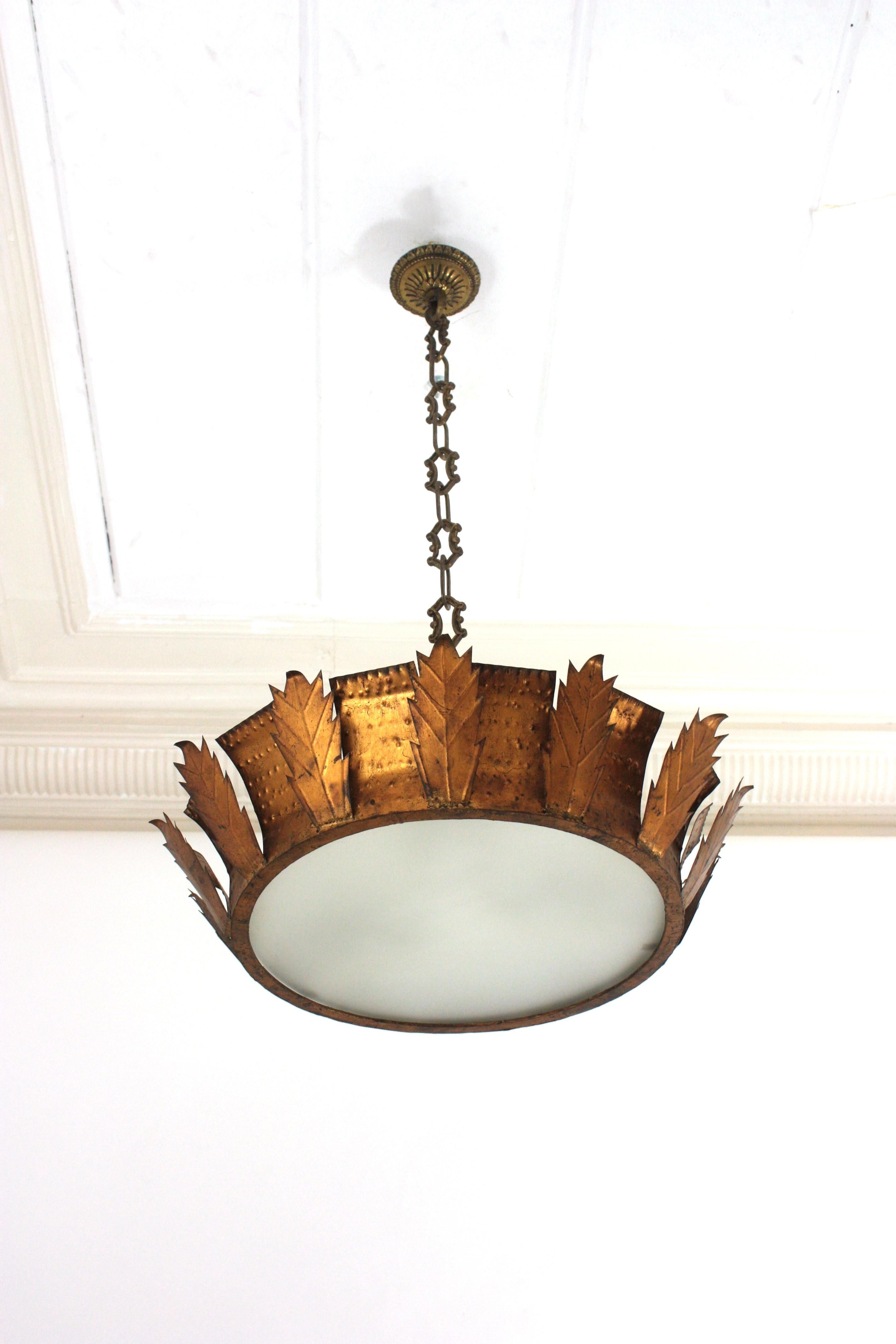 Large Sunburst Crown Flush Mount, Iron, Gold Leaf

Large hand-hammered iron  sunburst crown ceiling light fixture with frosted glass panel difusser. Spain, 1950s
This ceiling flush mount was handcrafted in Spain at the Mid-Century Modern period in