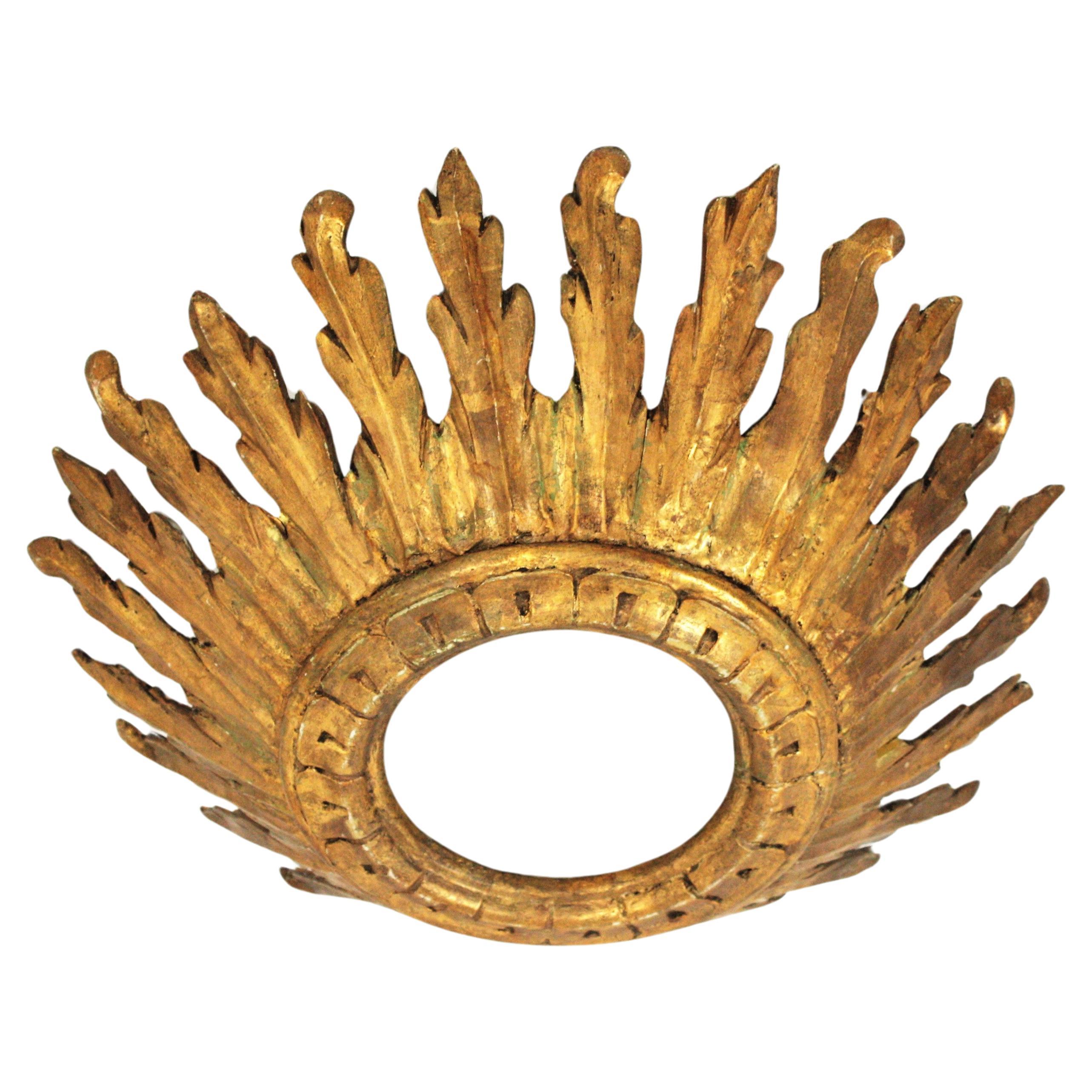 Monture encastrée en forme de couronne de soleil, bois doré, feuille d'or, Espagne, années 1930-1940.
Magnifique luminaire de style baroque en bois doré sculpté avec diffuseur en verre dépoli. 
Cette remarquable monture encastrée à couronne en