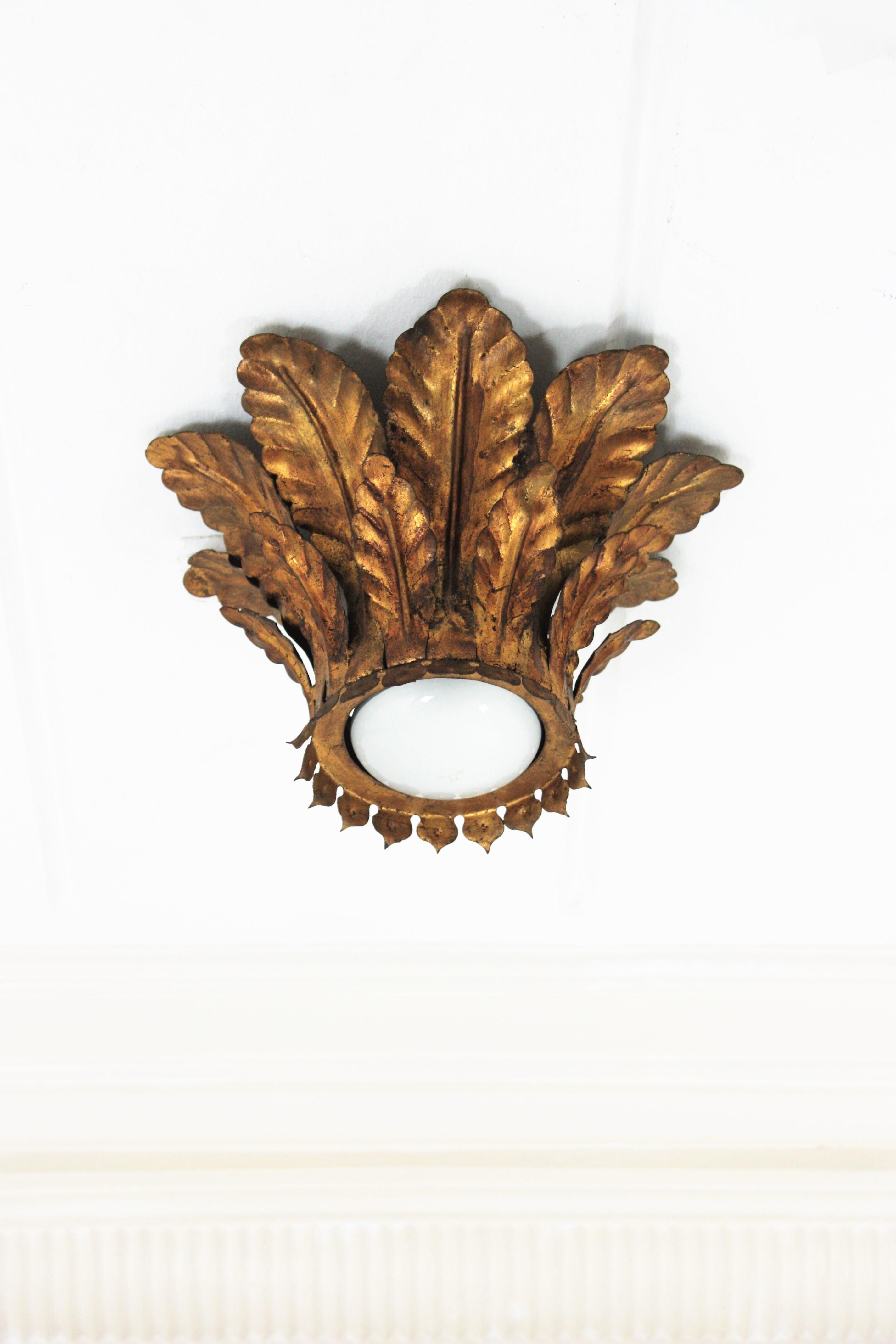 Sunburst light fixture with foliage frame, Gilt Wrought Iron, Spain, 1950s.
This eye-catching flush mount features a hancrafted crown shaped sunburst structure made of two layers of iron leaves surrounding a central light with an exposed bulb.