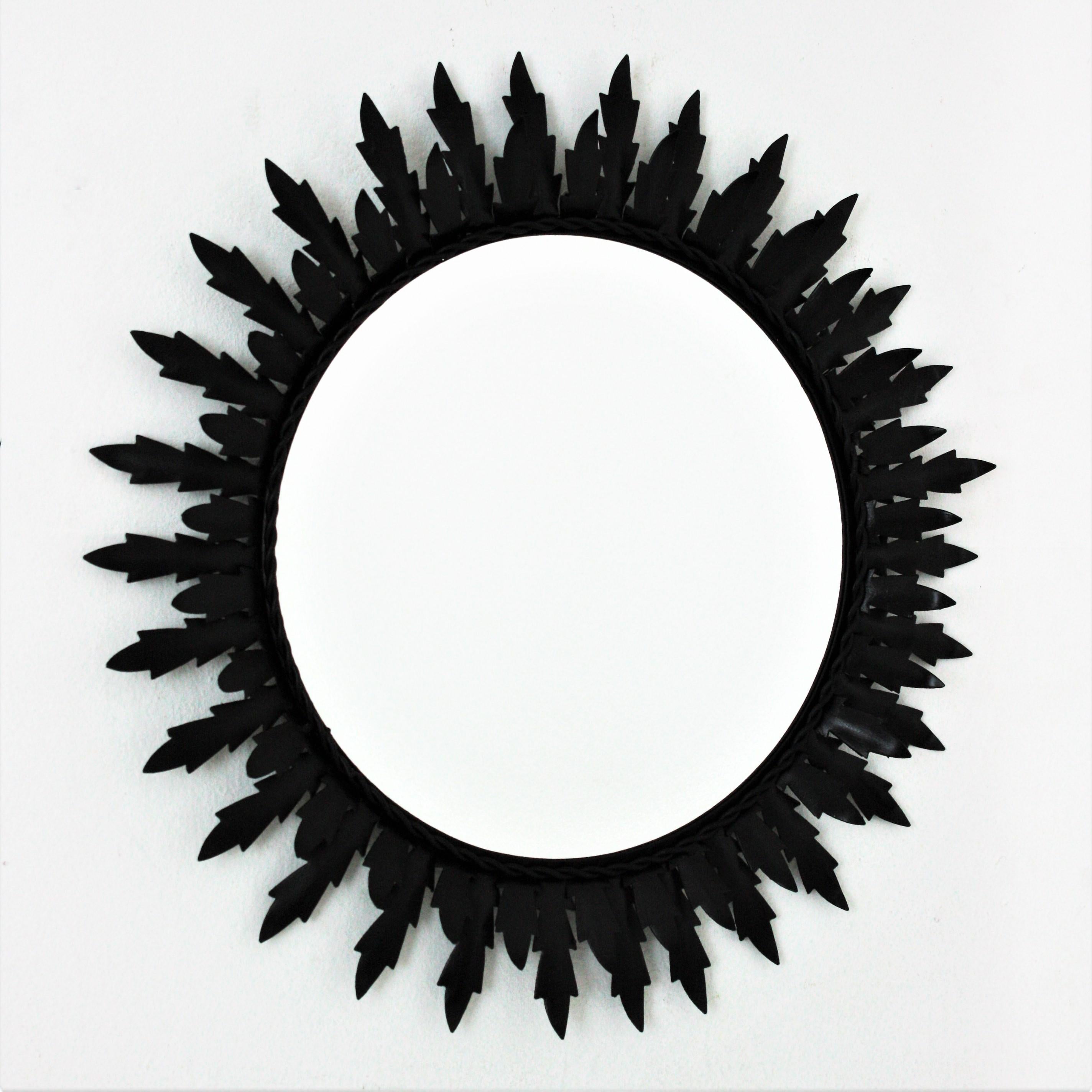 An eye-catching iron round sunburst mirror with black painted finishing, Spain, 1960s.
The frame is comprised by two layers of leaves surrounding the glass.
This wall mirror would be a nice addition in a contemporary or classical ambiance. Place