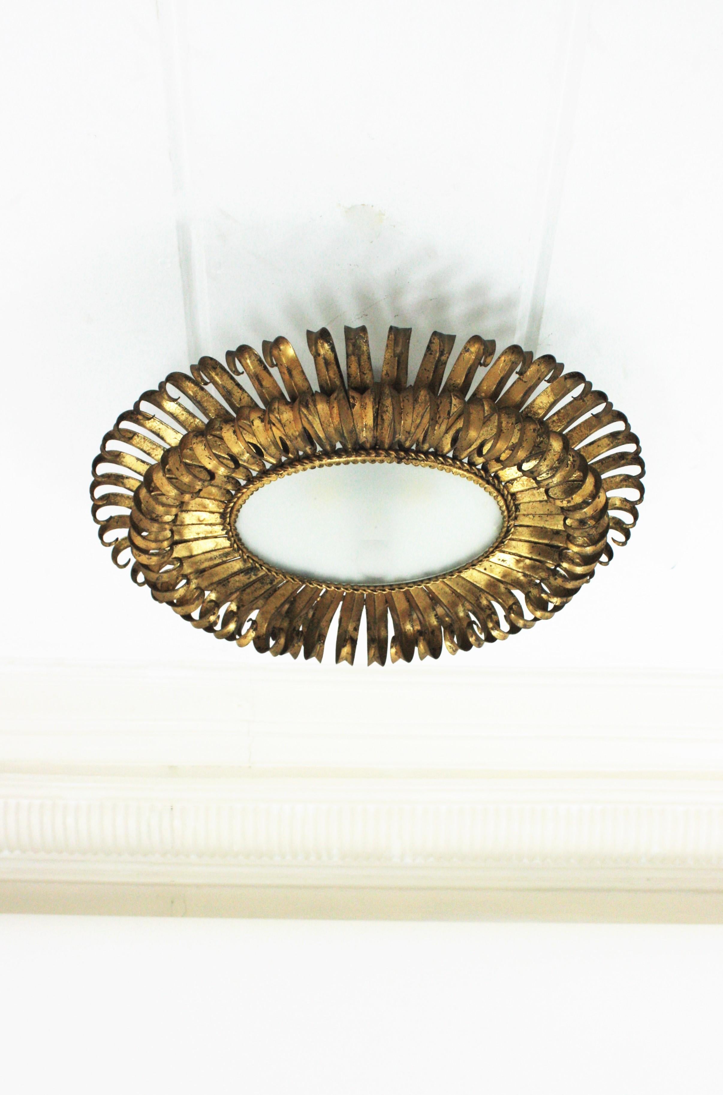 Stunning hand-hammered double layered eyelash gilt iron oval sunburst flush mount / pendant. France, 1950s. 
The frame is made by a double layer of curved beams in eyelash shape that makes the piece highly decorative. It has gold leaf finish and a